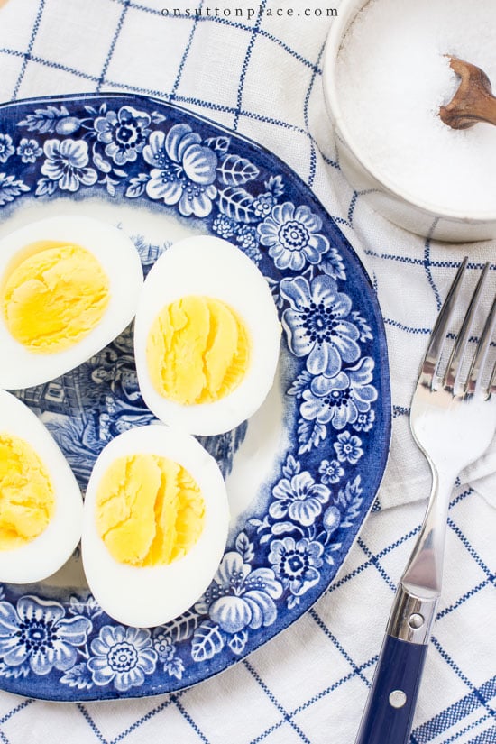 How to hard boil eggs so they peel perfectly every time! Learn how to boil eggs the easy way with these step by step directions. 2 eggs cut in half on blue plate