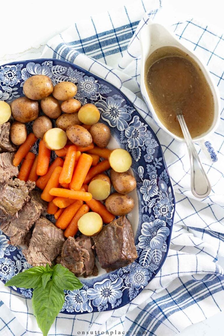 classic pot roast recipe on blue oval platter with gravy boat of broth