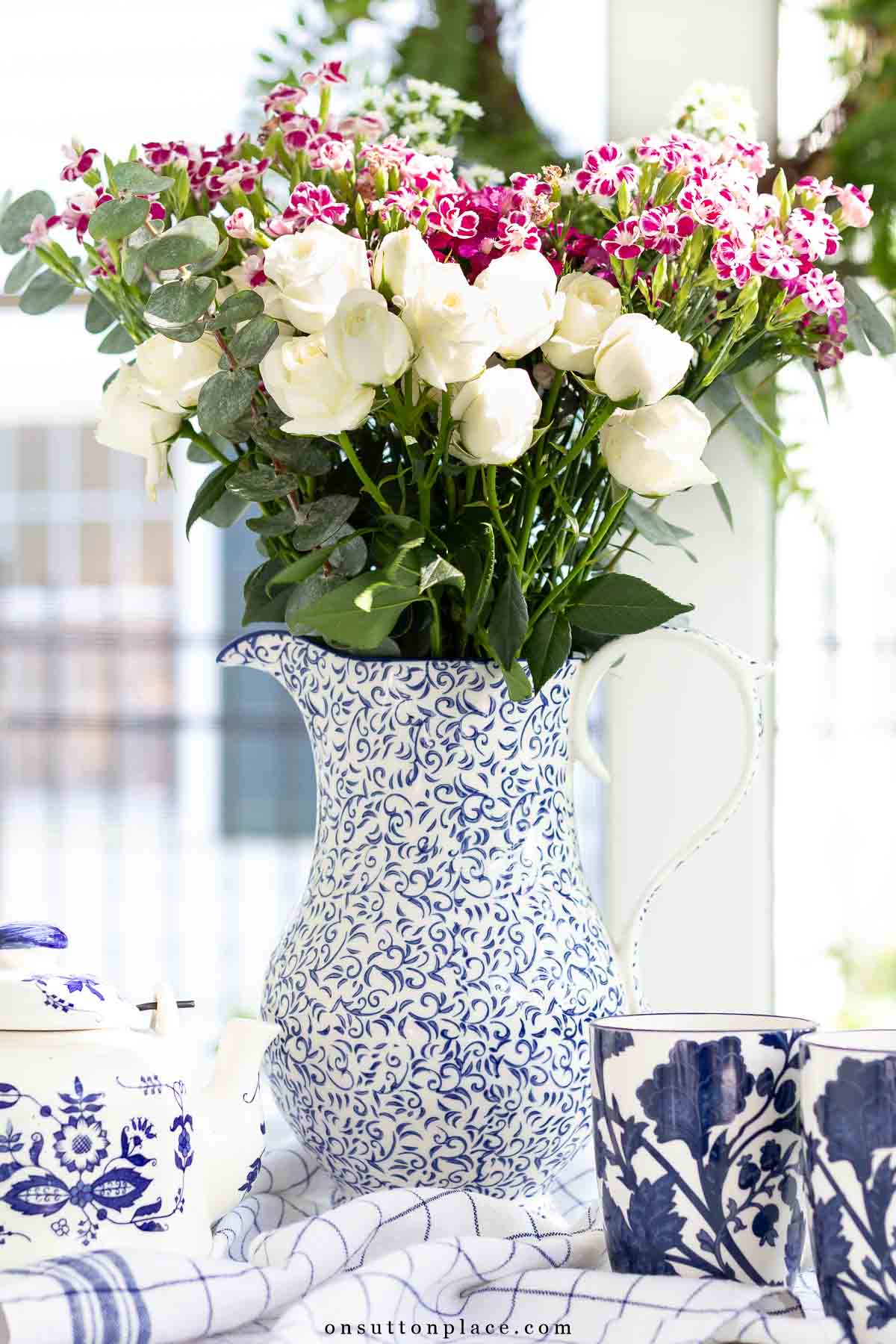 blue and white pitcher of flowers on screened in porch