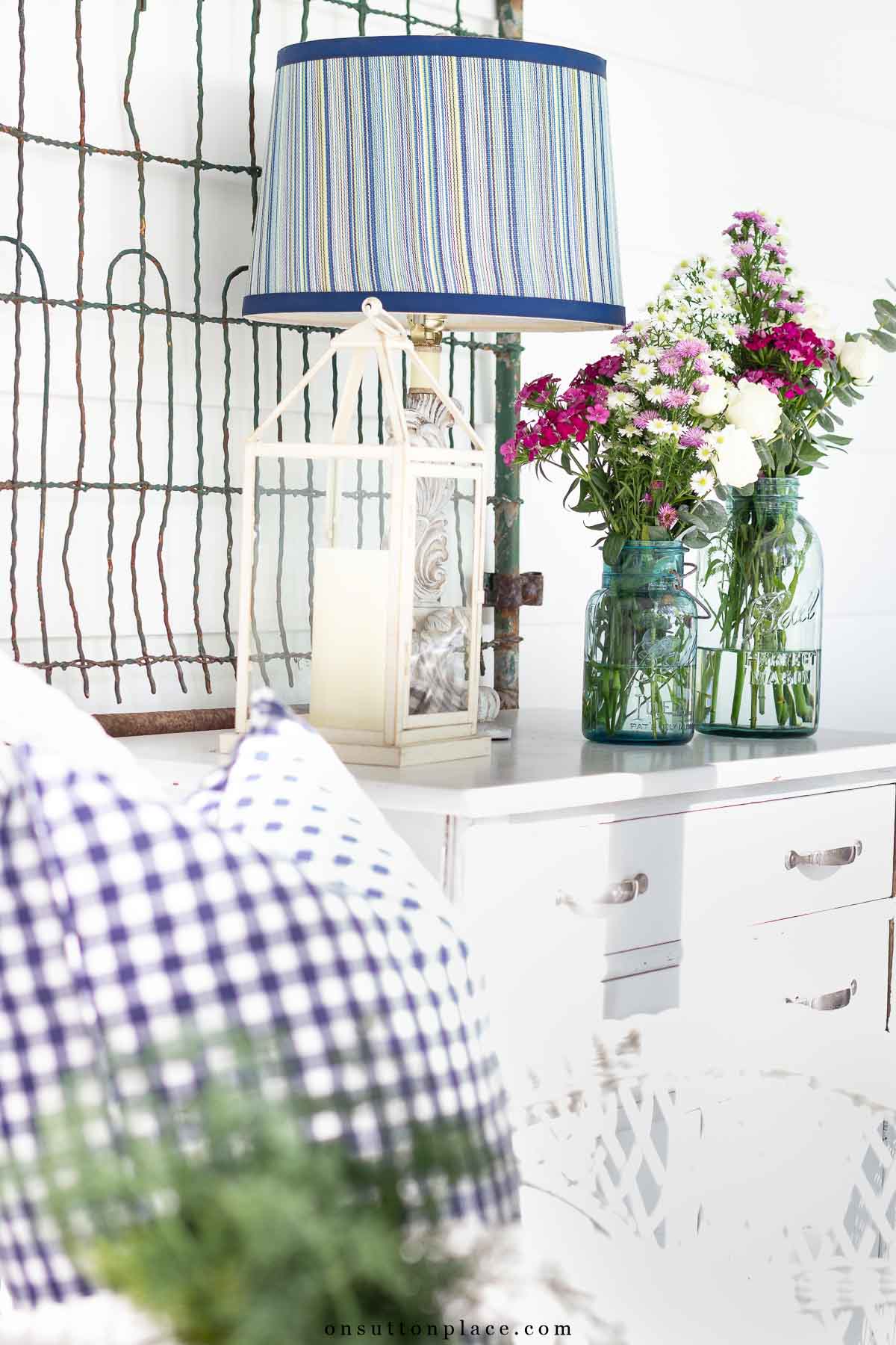 small back porch retreat with simple outdoor furniture lantern on white chest