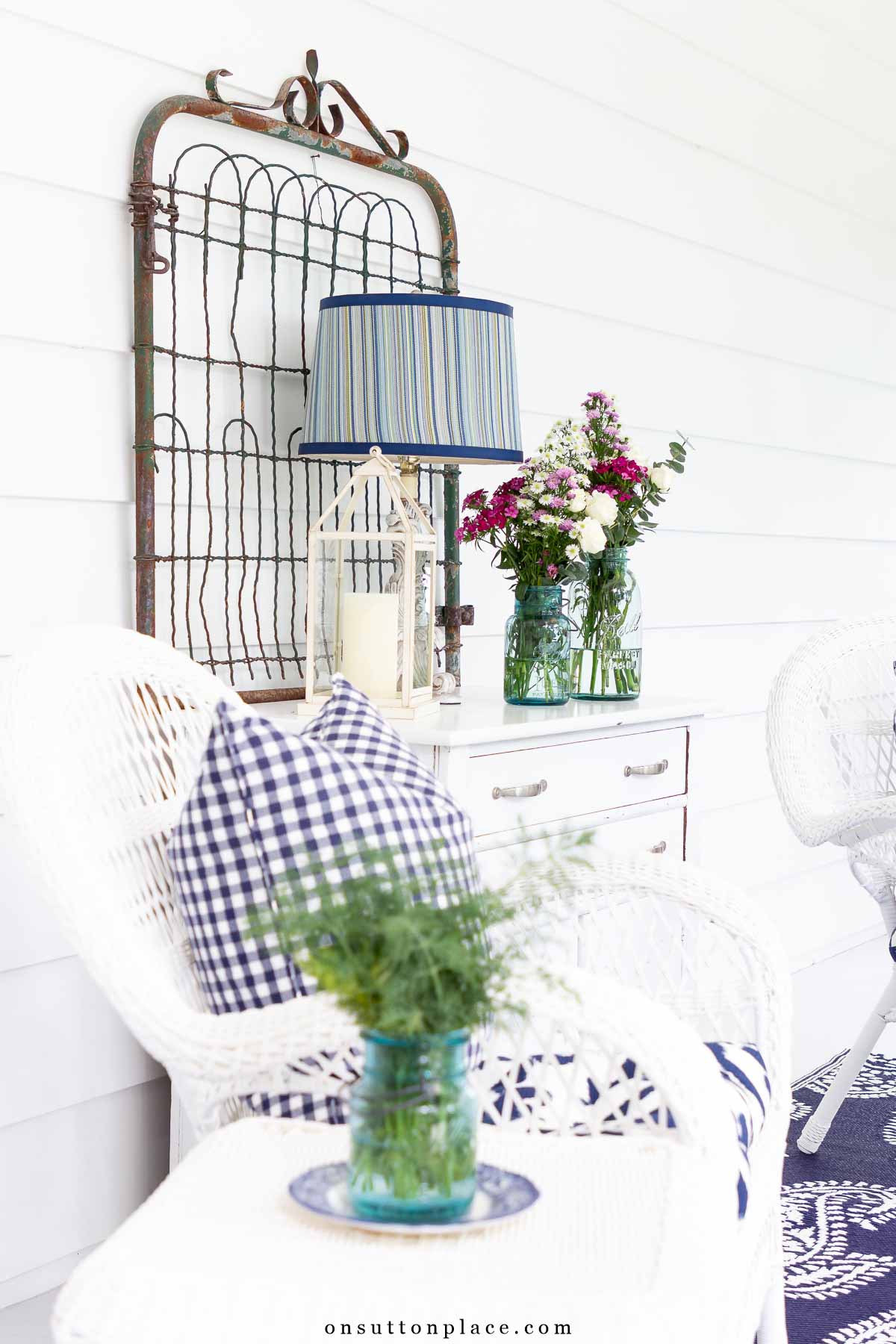 small screened in porch seating area with white chest and outdoor chairs