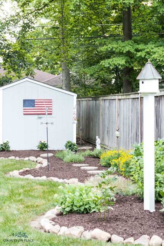garden along fence with storage shed and bird house
