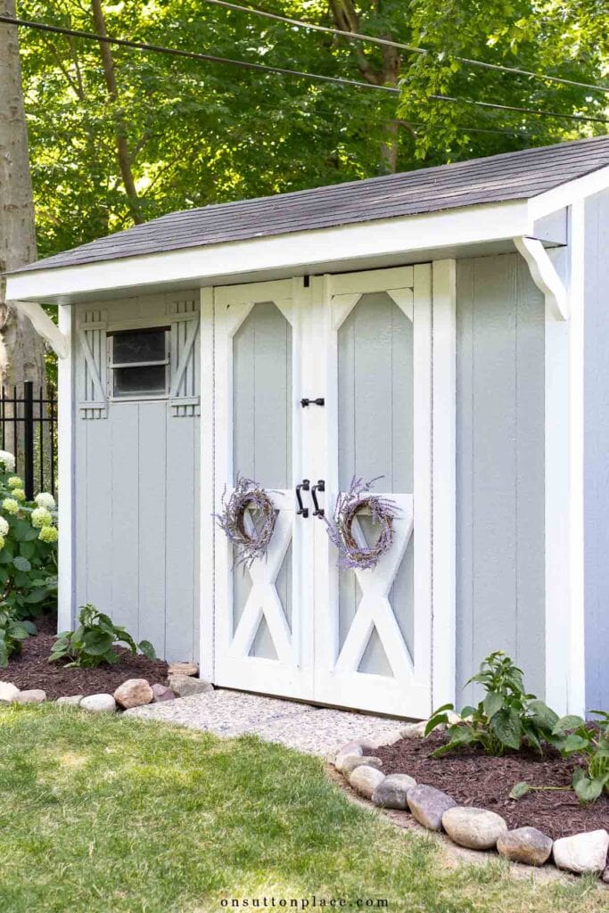 outdoor storage shed after renovation lavender wreaths gray and white paint