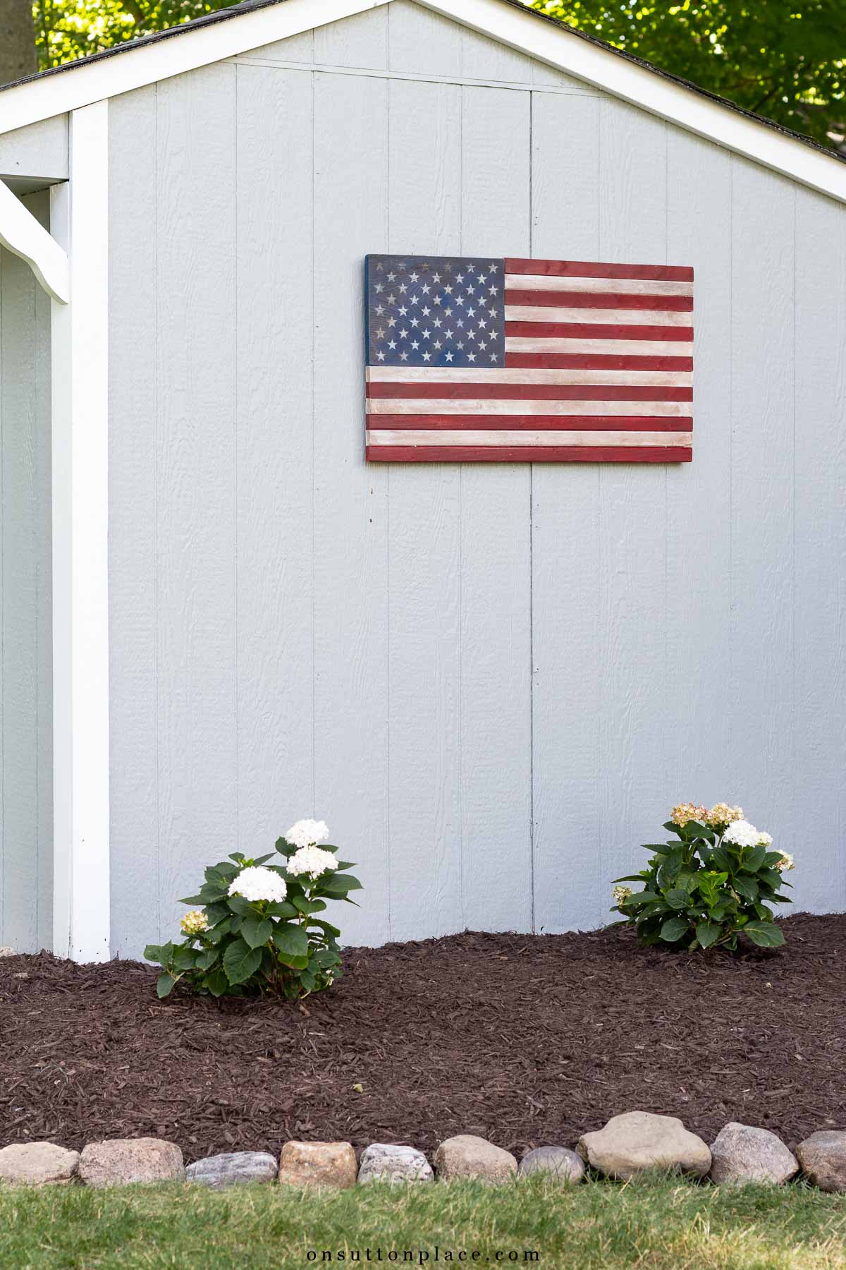 wood american flag on side of outdoor storage shed rock border
