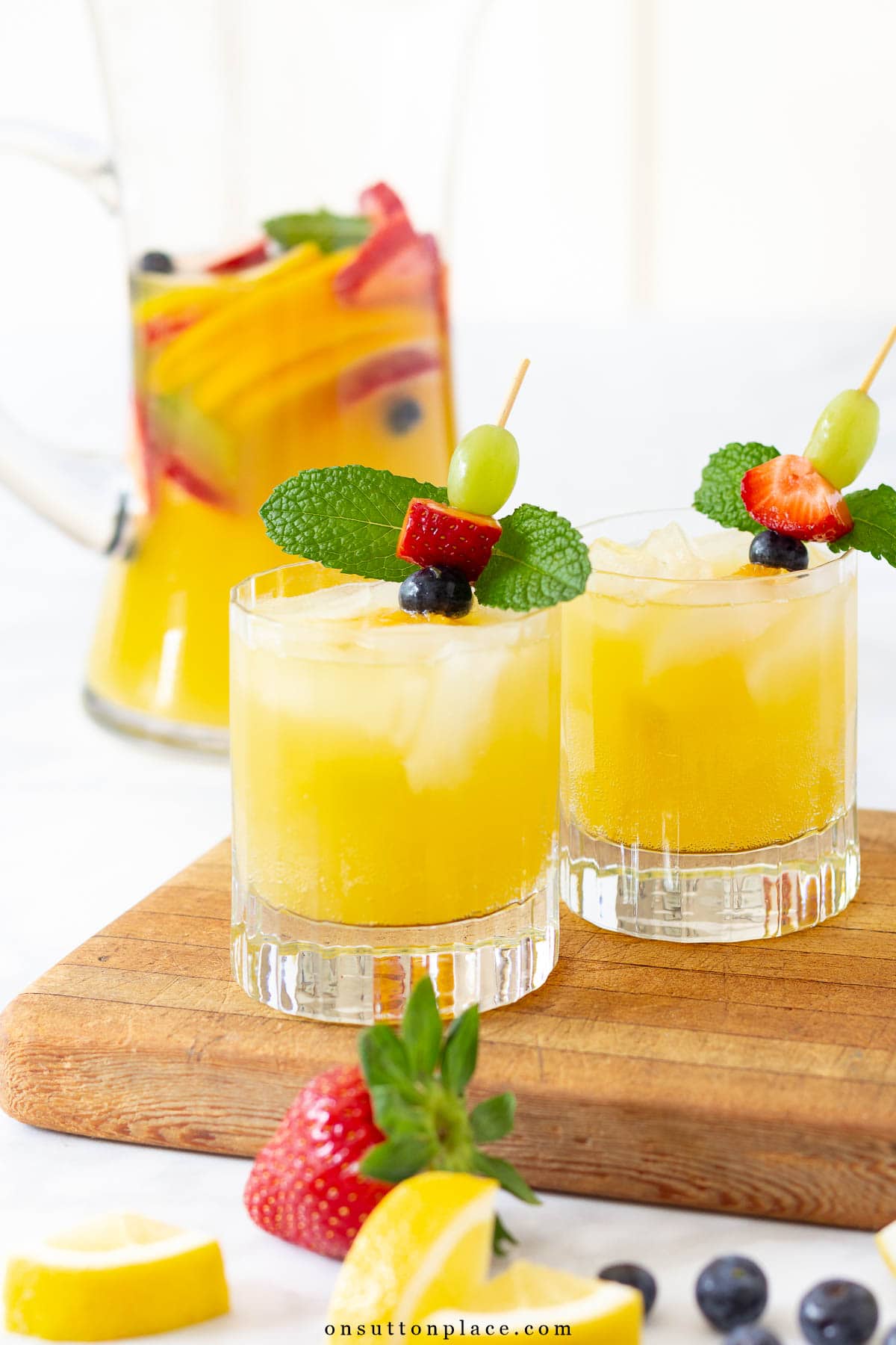 Make this non alcoholic white sangria recipe for your summer gatherings. Fresh fruit and tasty mint add just the right amount of flavor. So delicious! glasses of non alcoholic white sangria with garnish