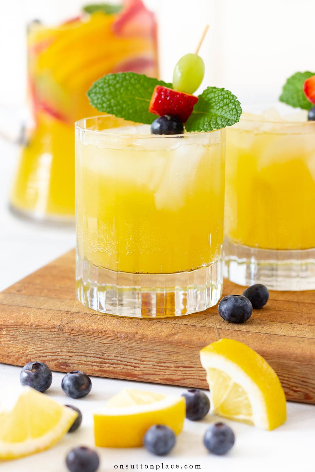 Make this non alcoholic white sangria recipe for your summer gatherings. Fresh fruit and tasty mint add just the right amount of flavor. So delicious! non alcholic white sangria recipe with fruit garnish