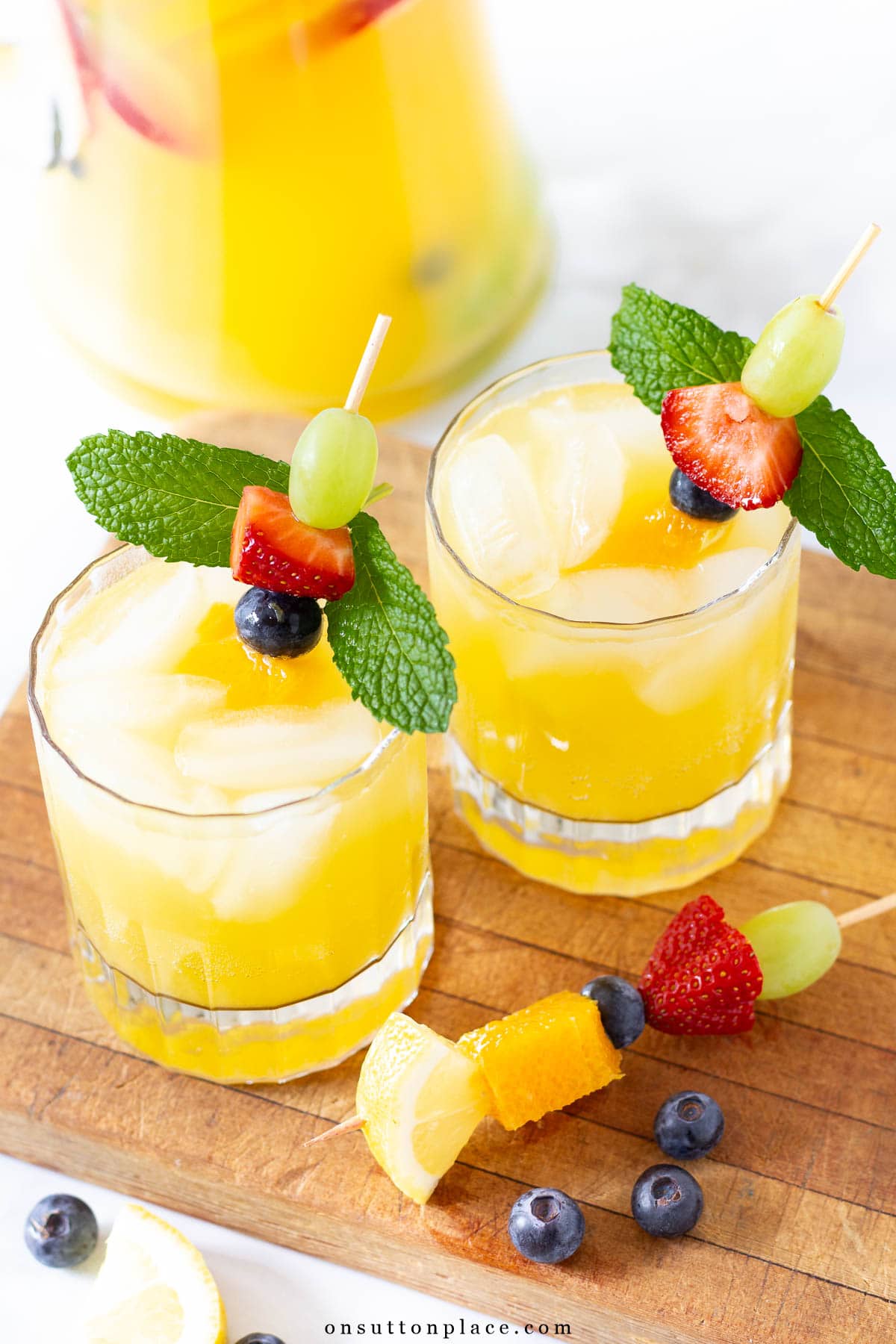 Make this non alcoholic white sangria recipe for your summer gatherings. Fresh fruit and tasty mint add just the right amount of flavor. So delicious! white sangria mocktail recipe in clear glasses