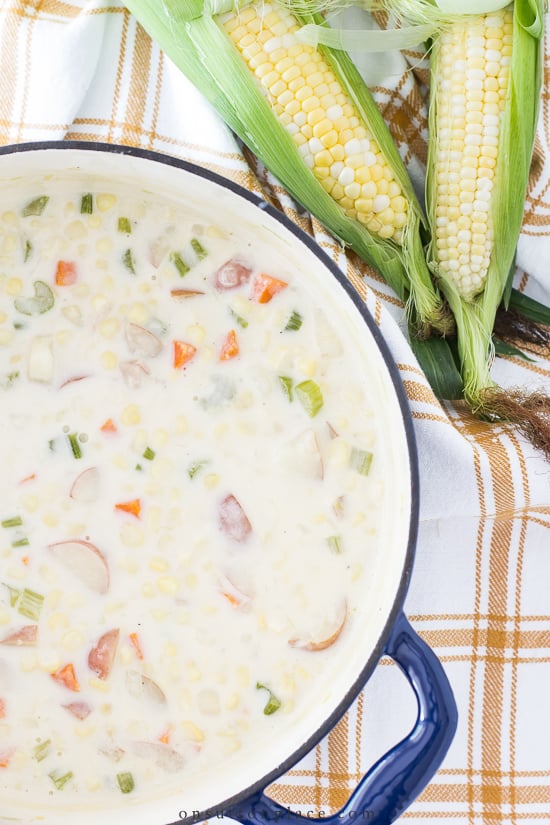 corn chowder in blue pot with ears of corn
