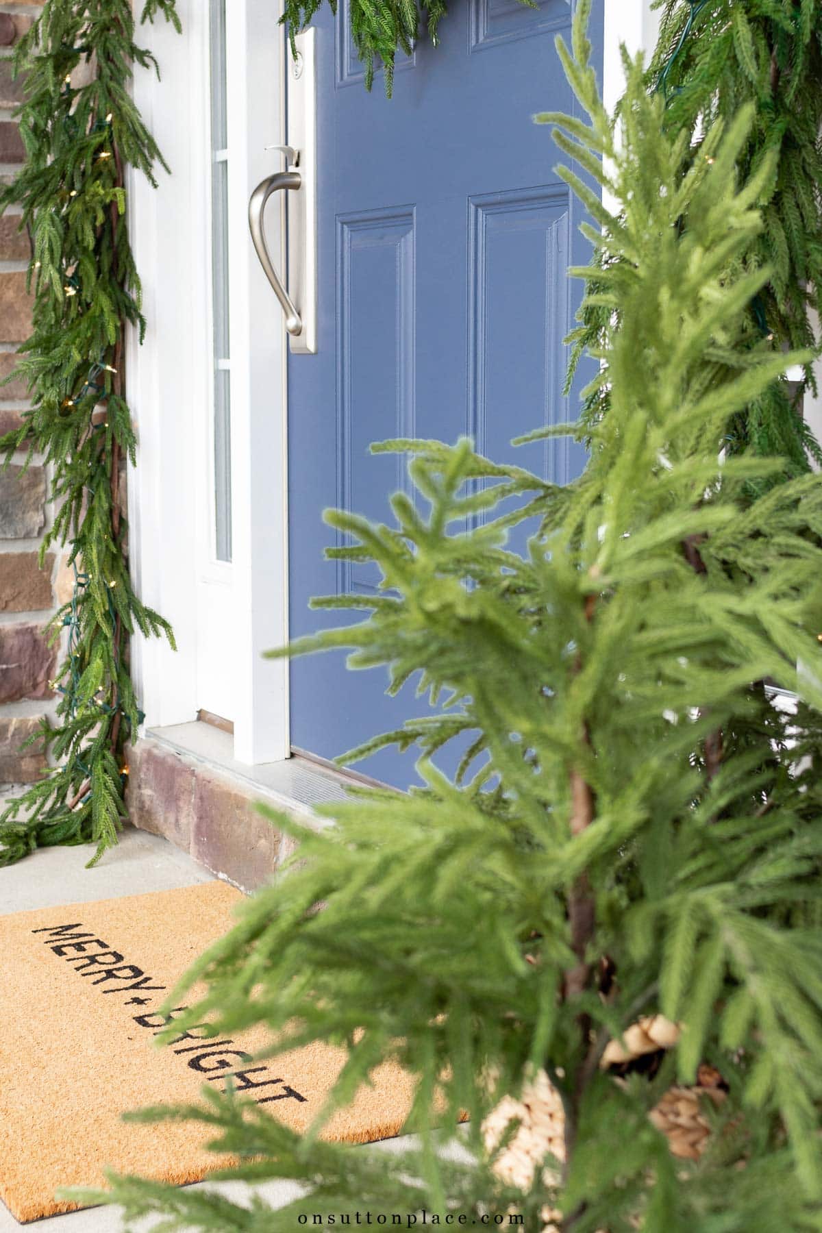 blue front door with Christmas doormat