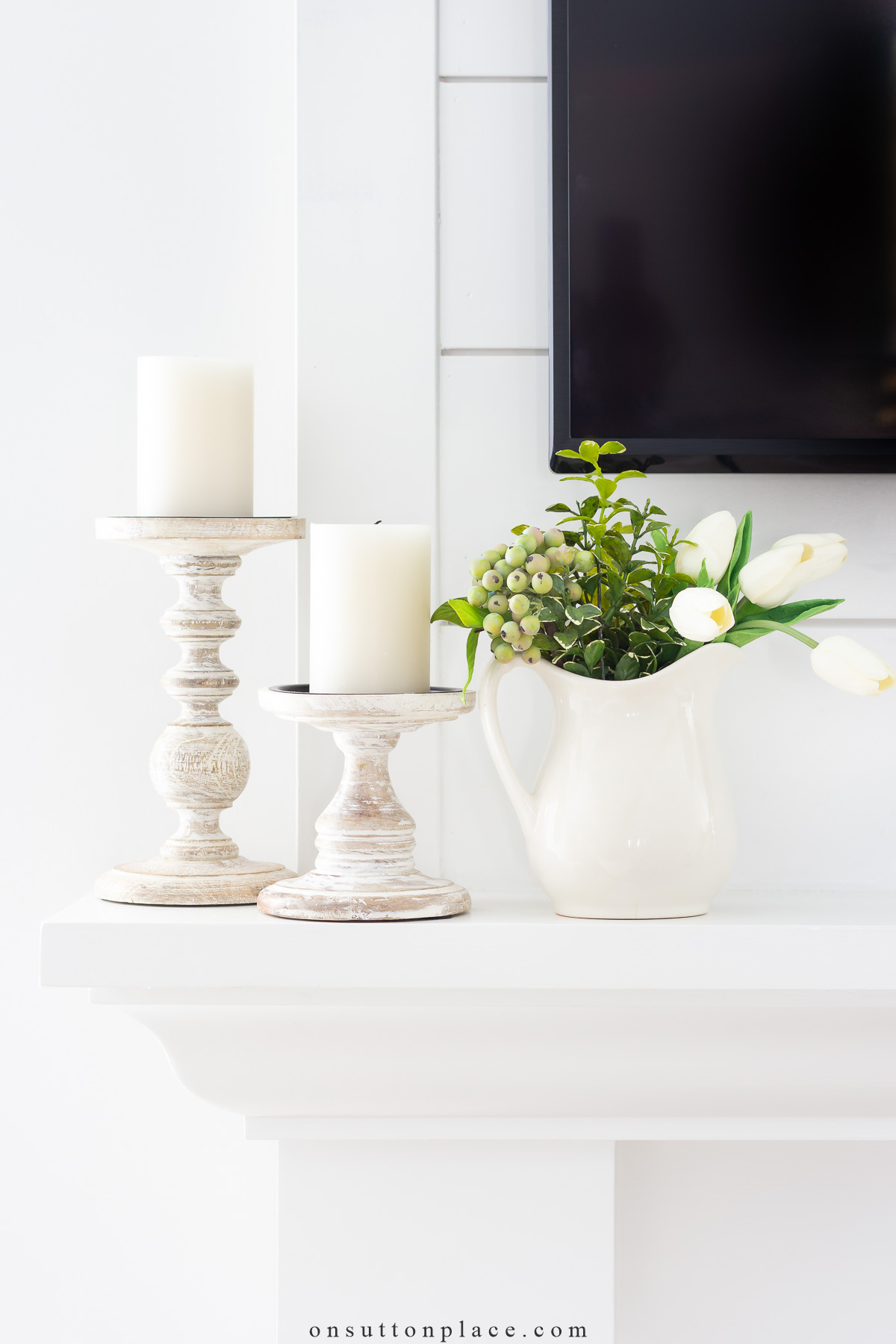 spring decor idea wood candle holders on mantel with pitcher of greenery
