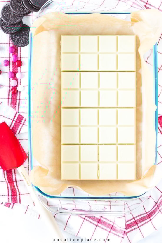 An easy white chocolate bark recipe that can be adapted for any holiday or any occasion. Includes a long list of variations that make this recipe so versatile. I also answer the question is white chocolate really chocolate? white chocolate bars in baking dish