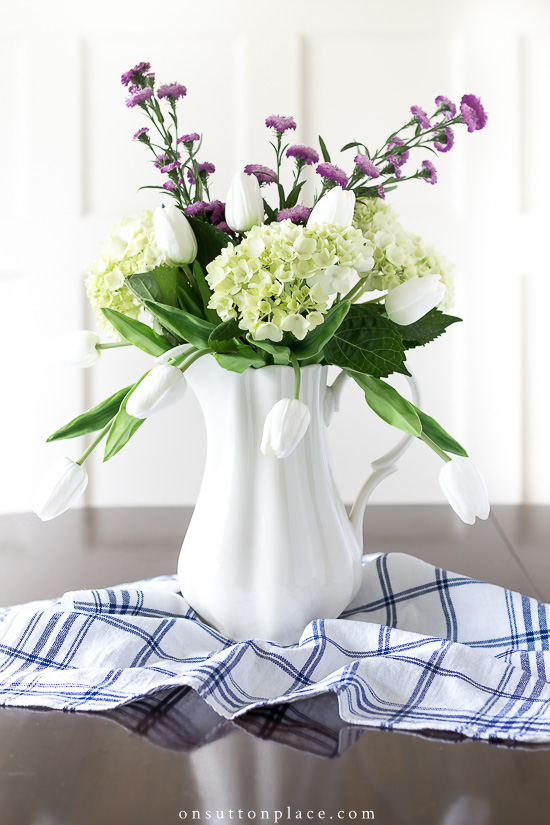 Do you know how to decorate with different kinds of flowers? The answer is broken down into specific kinds of flowers, vessels, & adding faux flowers. flower designs in white pitcher