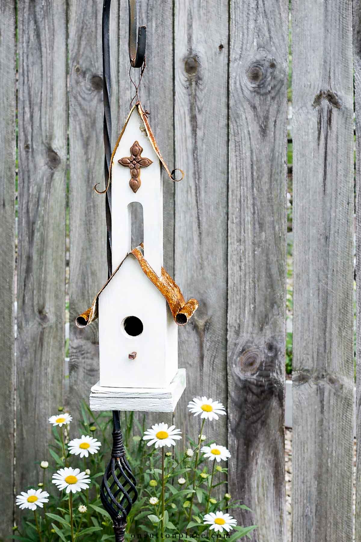 church birdhouse with shasta daisies on shepherd hook