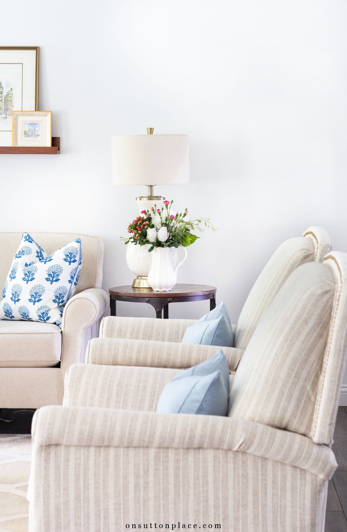 two sitting chairs with blue pillows in neutral living room