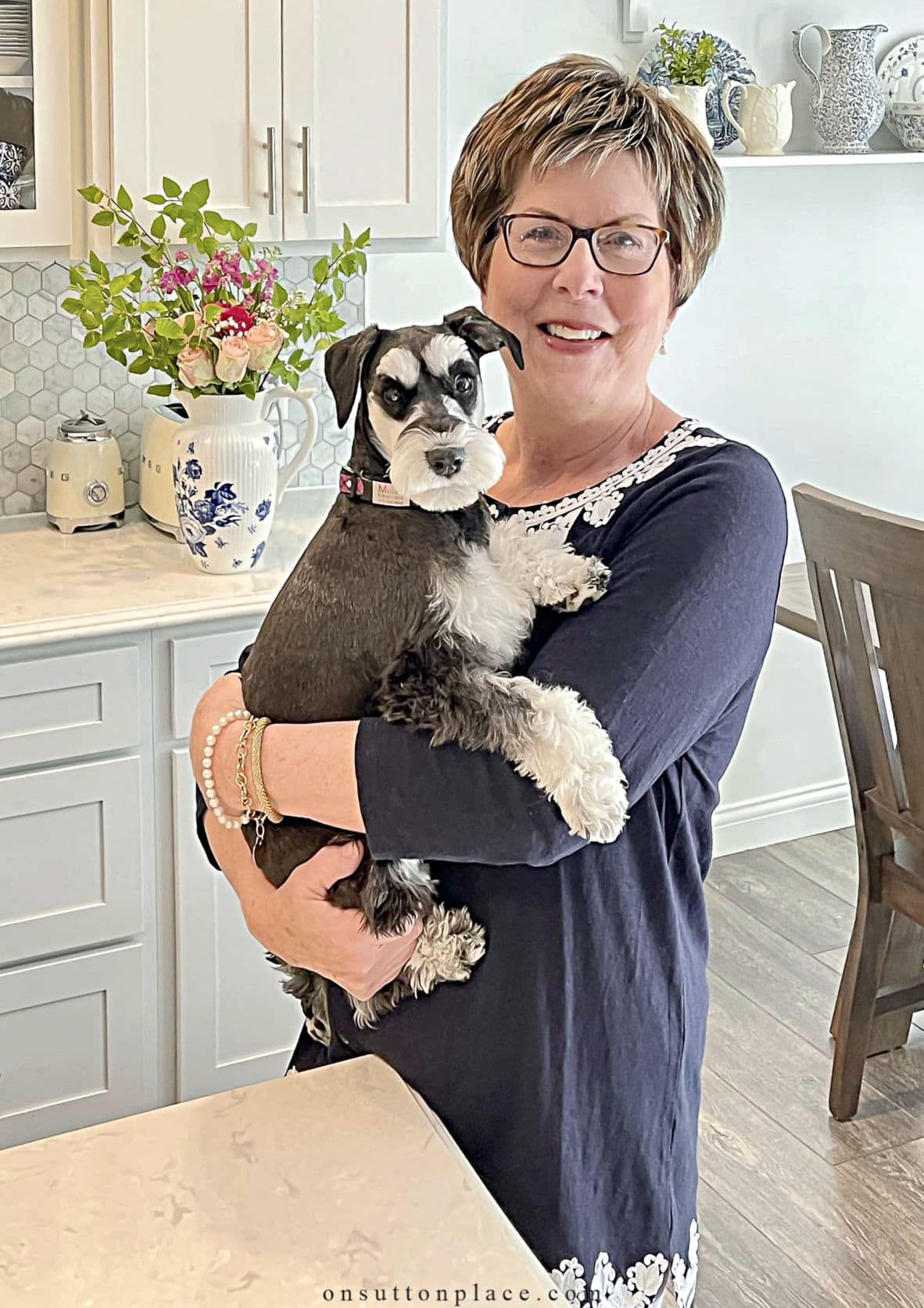 Ann Drake holding her miniature schnauzer Millie in her kitchen 1