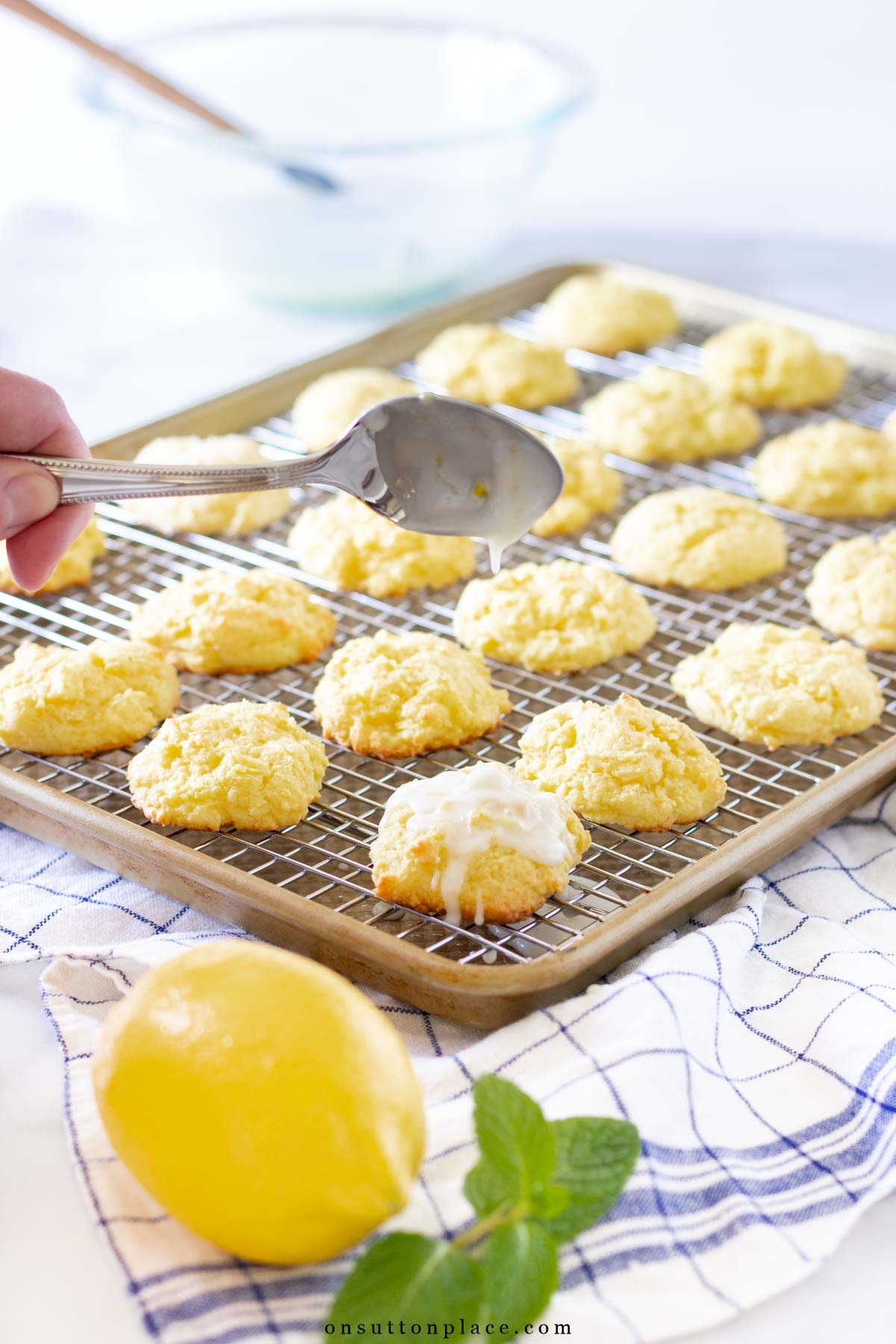 baking sheet of lemon cookies with spoon dripping glaze