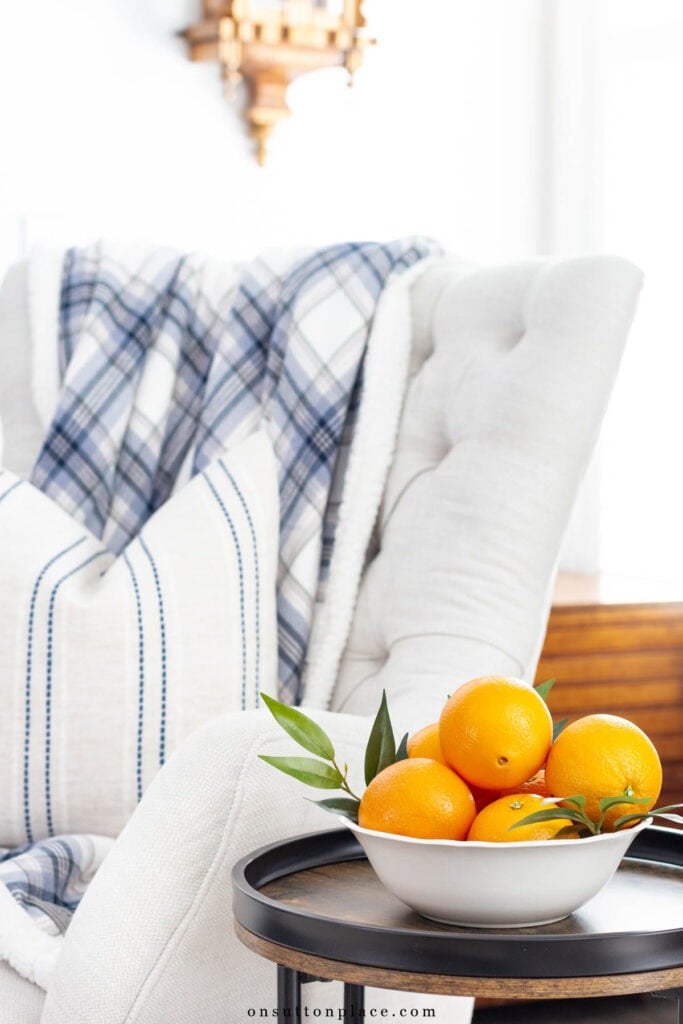 neutral living room ideas tufted chair with throw blanket and pillow oranges in bowl