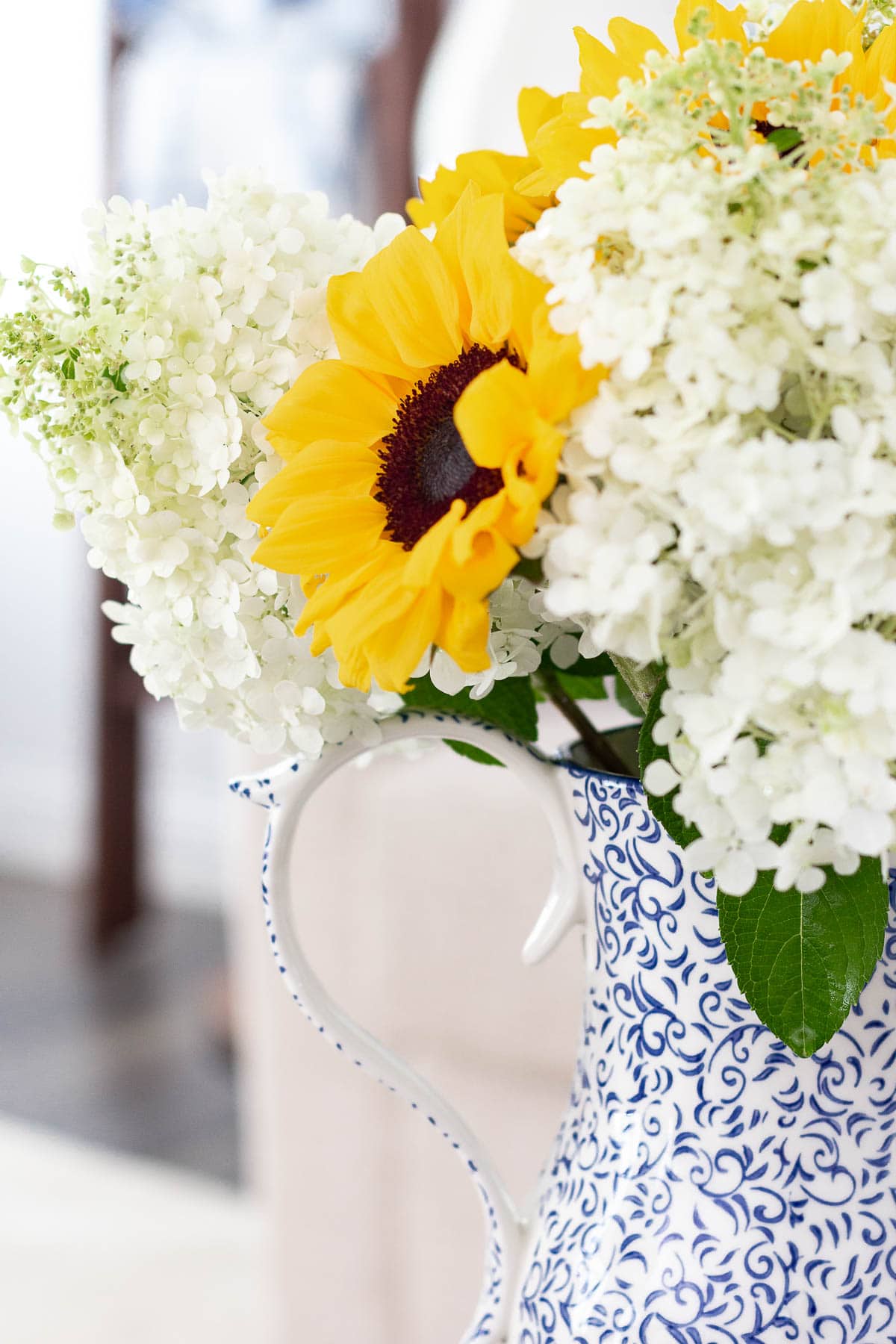 sunflower and hydrangea arrangement in white and blue pitcher
