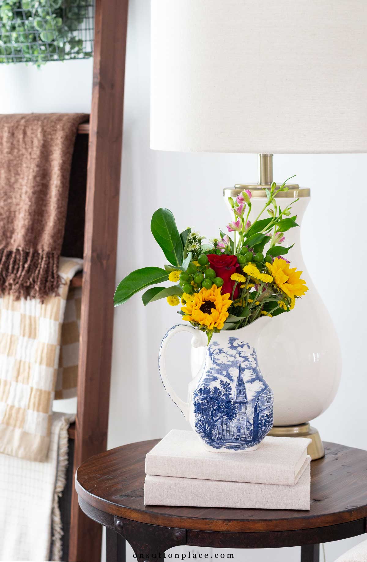 fall vignette idea flowers in fall colors in pitcher with books stacked underneath