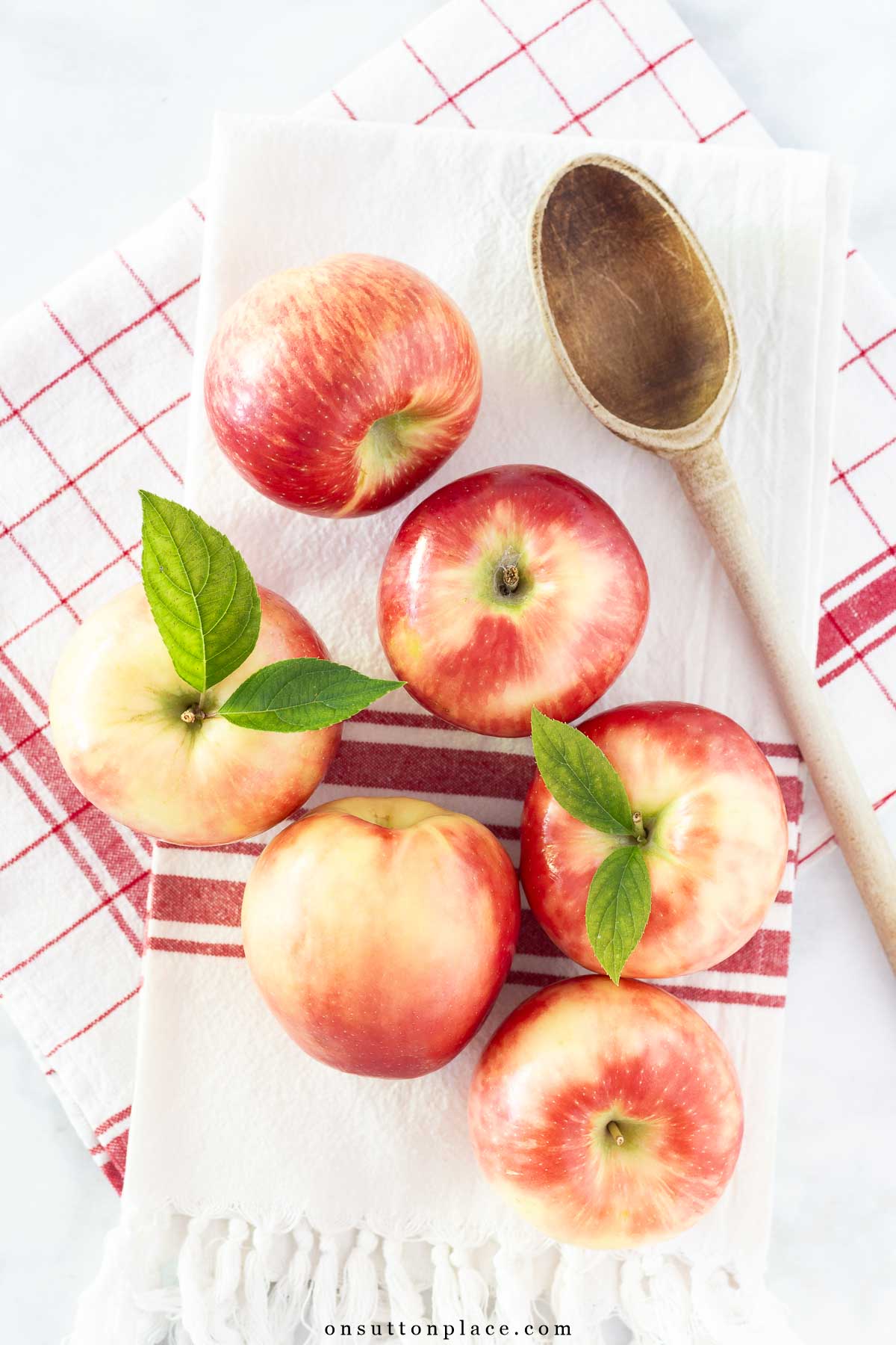 honeycrisp apples on red and white towels with wooden spoon