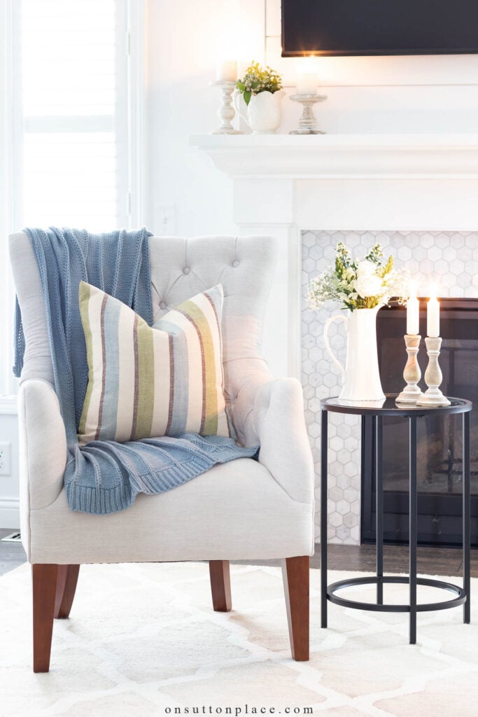 ivory chair with blue throw blanket and striped pillow beside round table tips for a simpler life