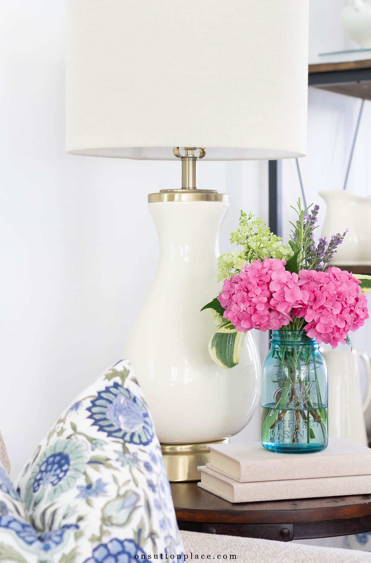 blue mason jar with flowers on side table with lamp
