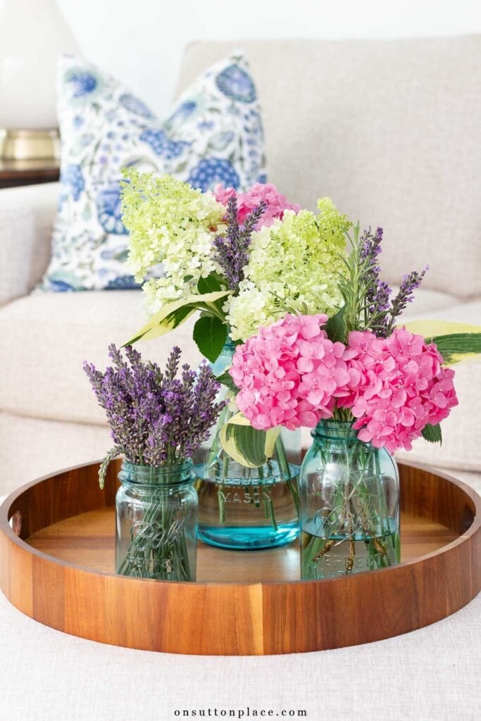 collection of mason jars with flowers on wood tray