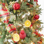 christmas tree with green and red plaid ribbon, red ornaments, orange slices lightened