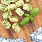 basil chiffonade in frozen olive oil on round wood board