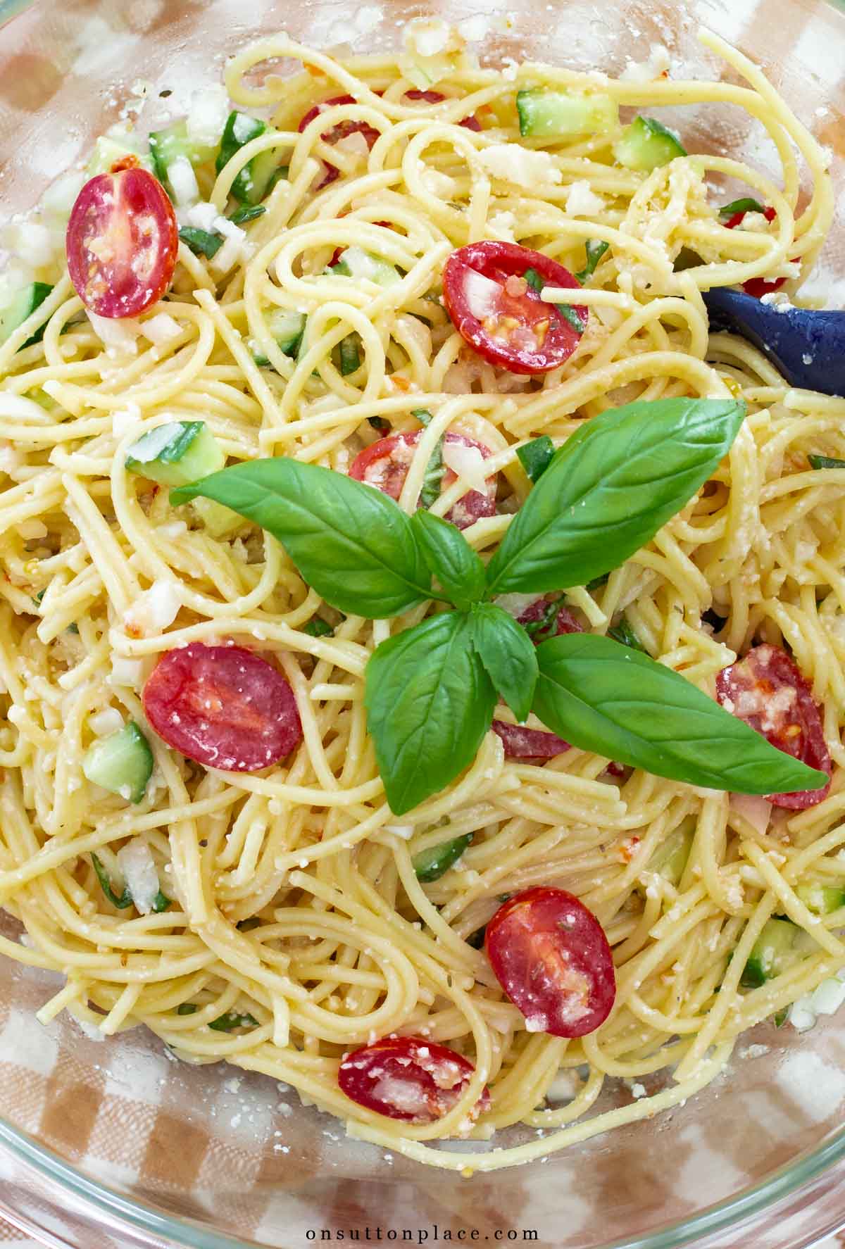 cold spaghetti salad recipe in bowl with sprig of basil
