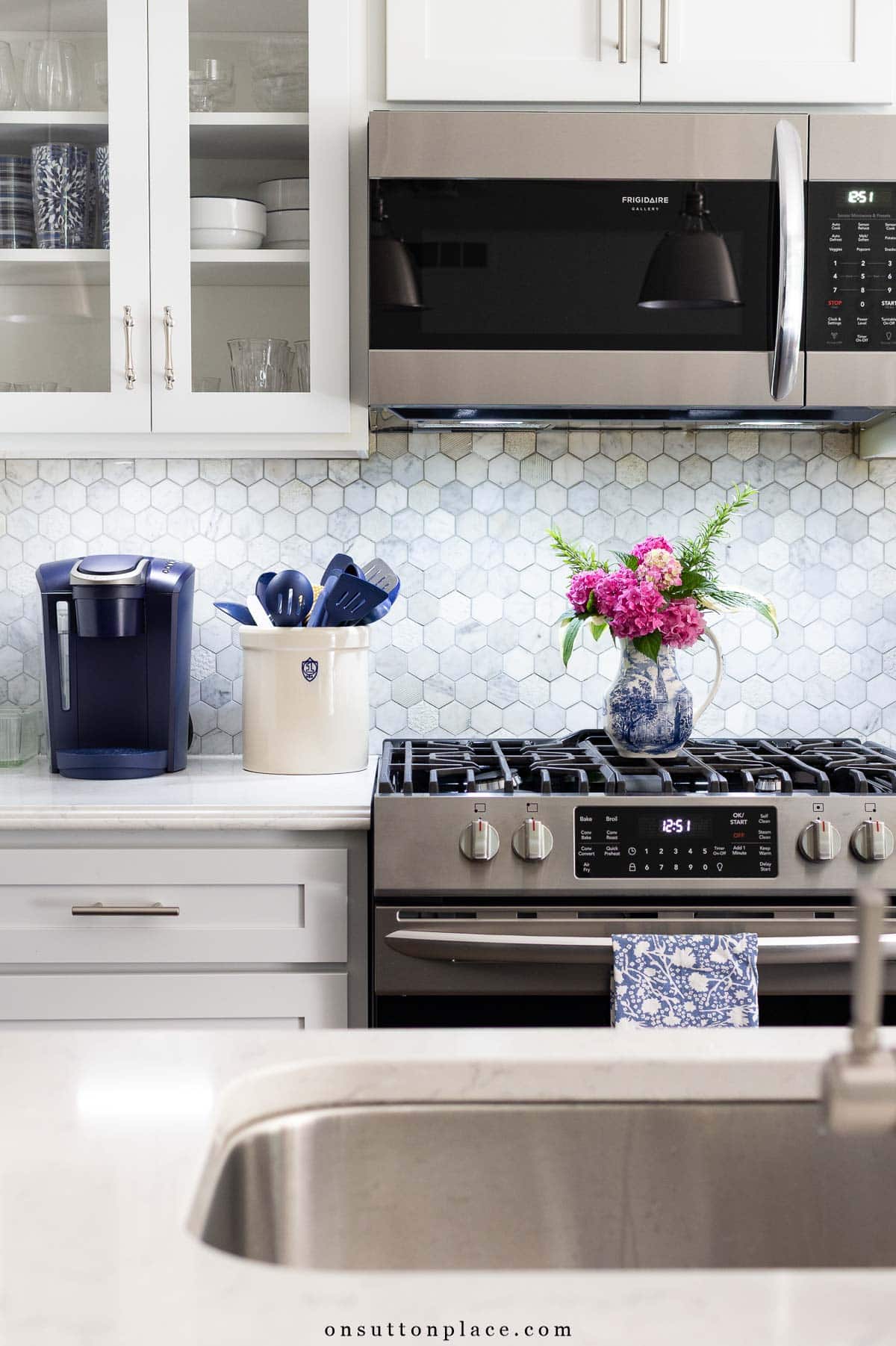 white kitchen with glass doors and gray tile backsplash under cabinet lighting