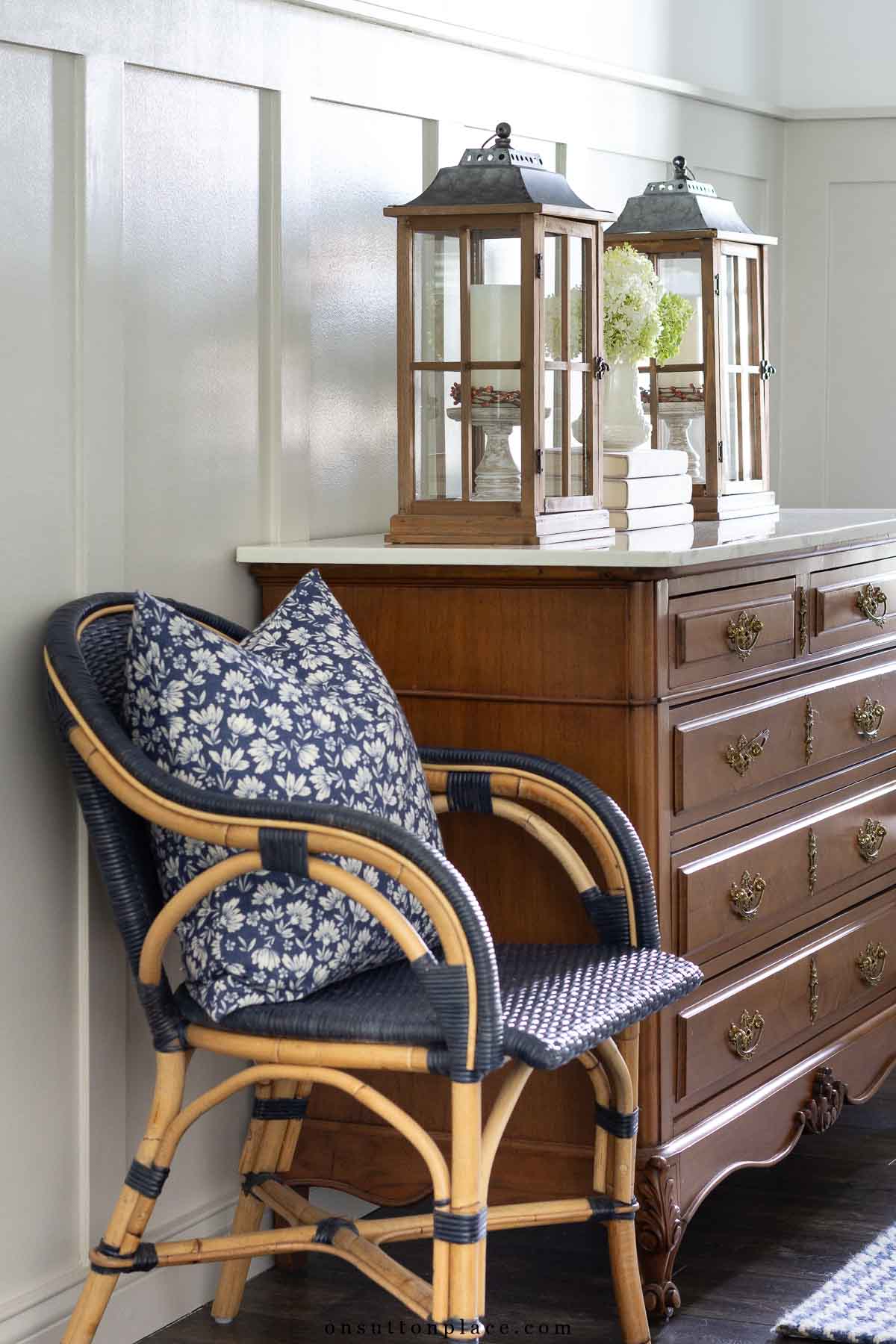 board and batten walls in foyer block print pillow on wicker armchair lanterns on vintage dresser