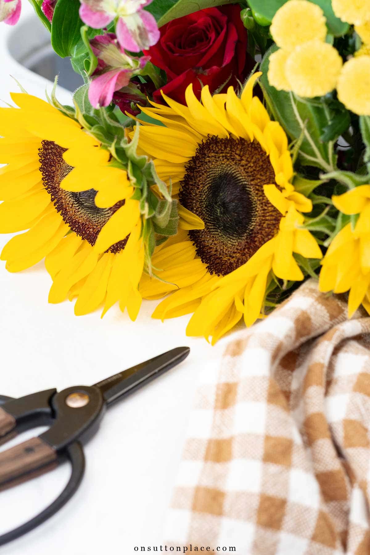 close up of sunflower bouquet checked towel and garden scissors
