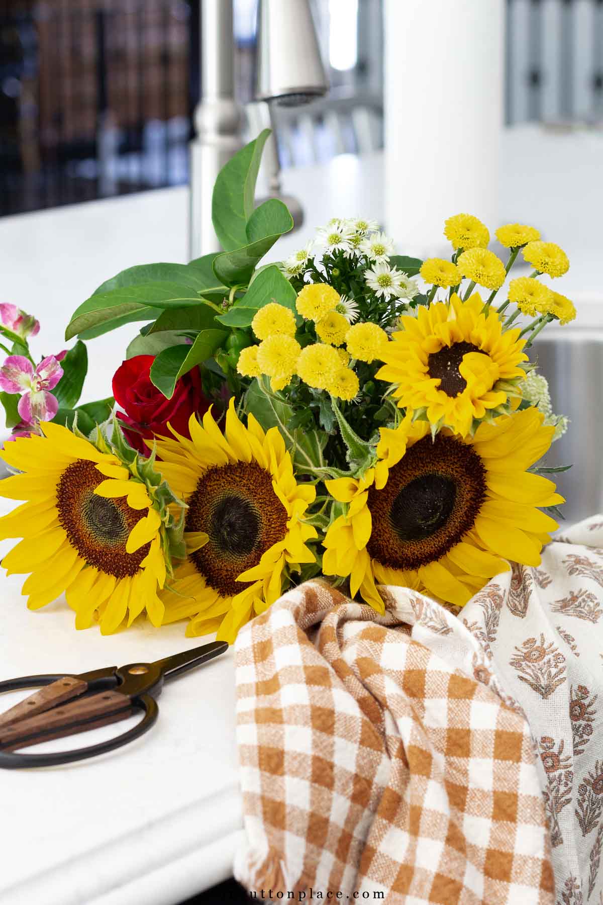 fall sunflower bouquet in kitchen sink with checked tea towel