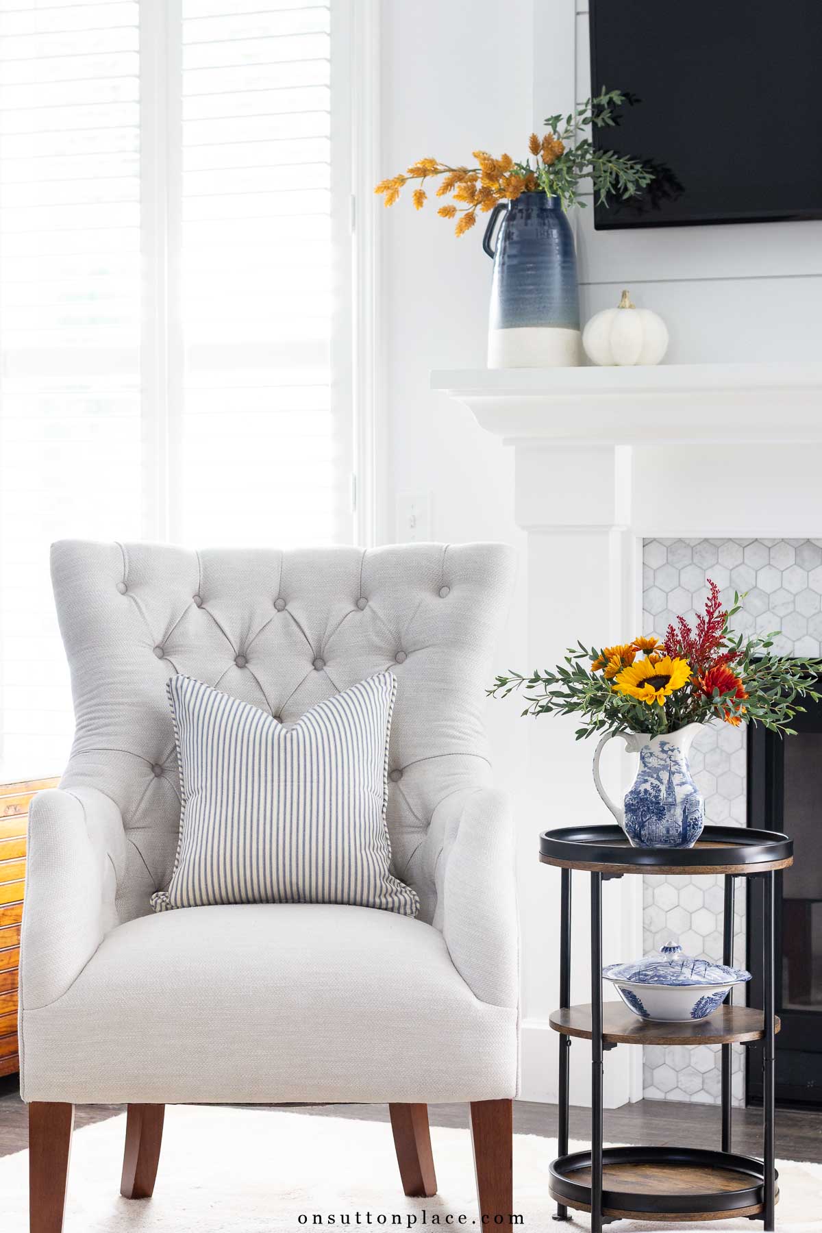 fall vignette with tufted chair blue ticking pillow mantel with autumn decor