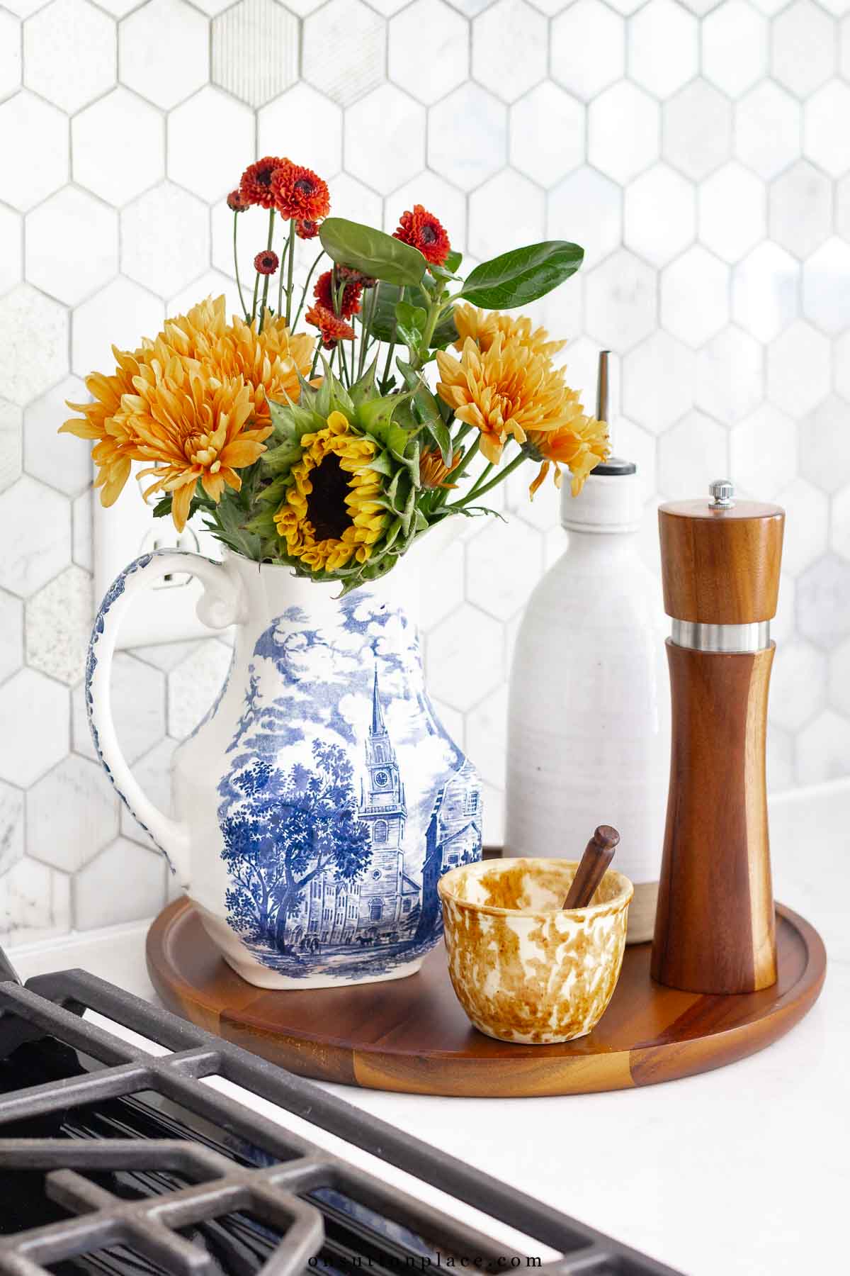 round tray beside stove with fall flowers