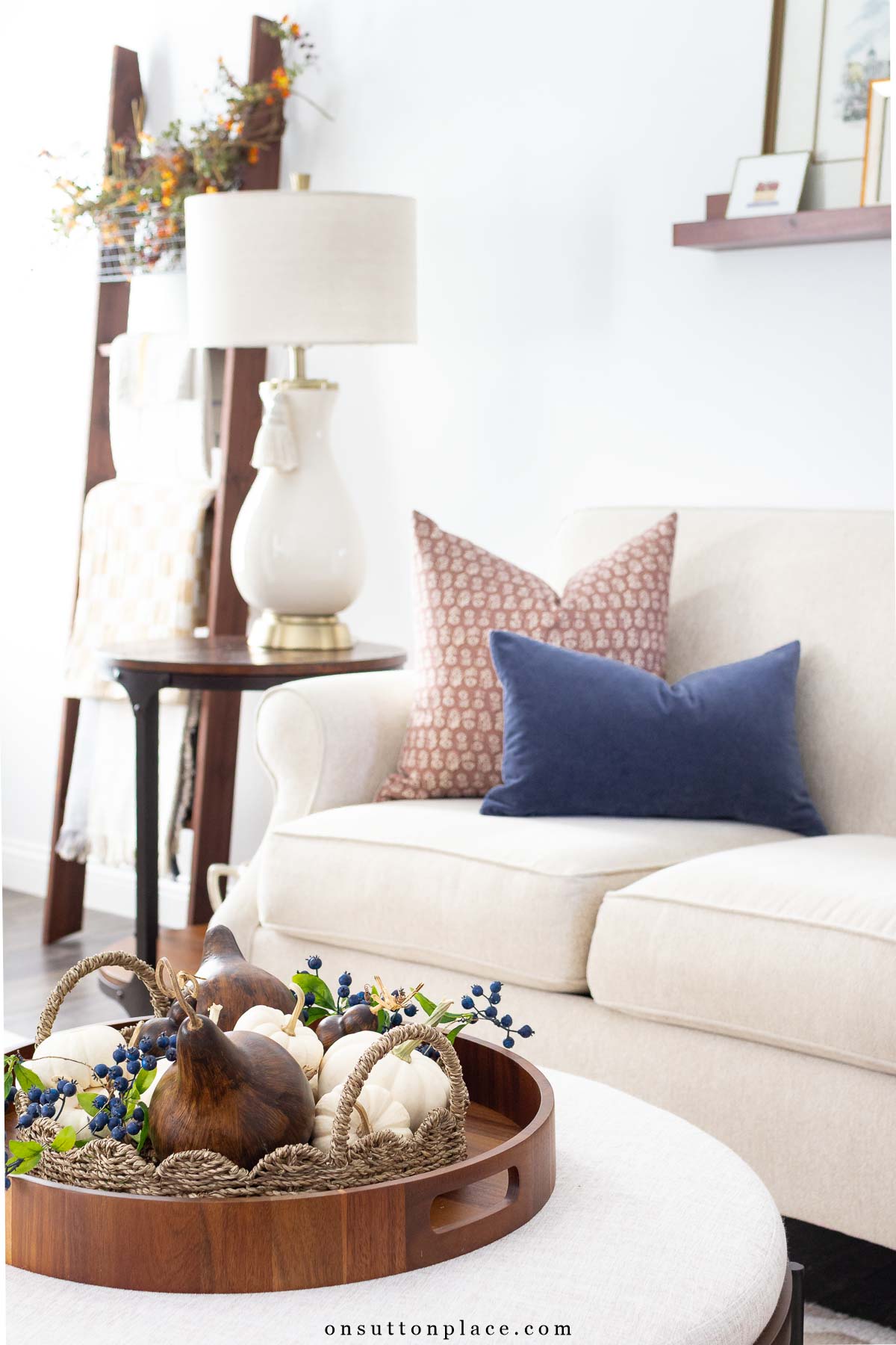 small white pumpkins and dried gourds in rattan tray with faux blueberry vine