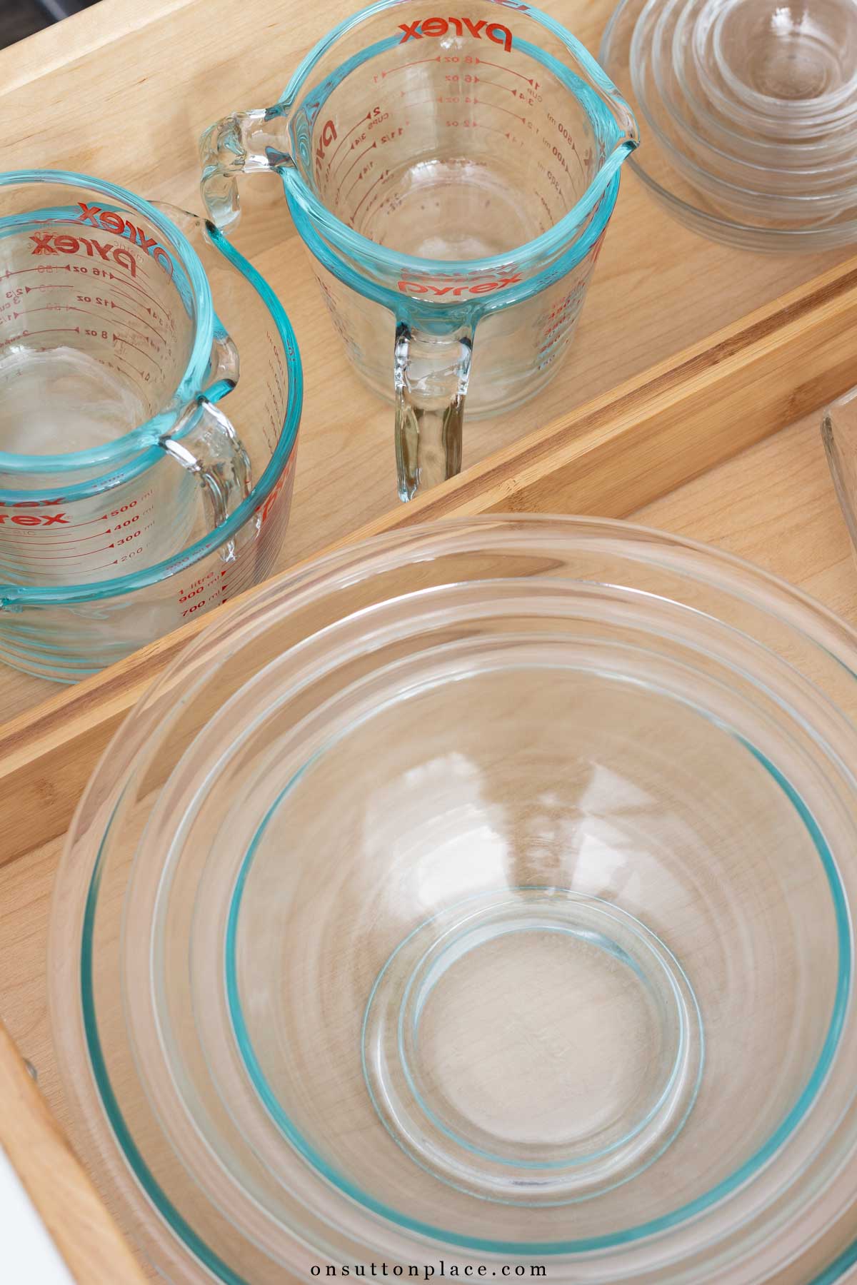 Pyrex mixing bowls and measuring cups in organized drawer