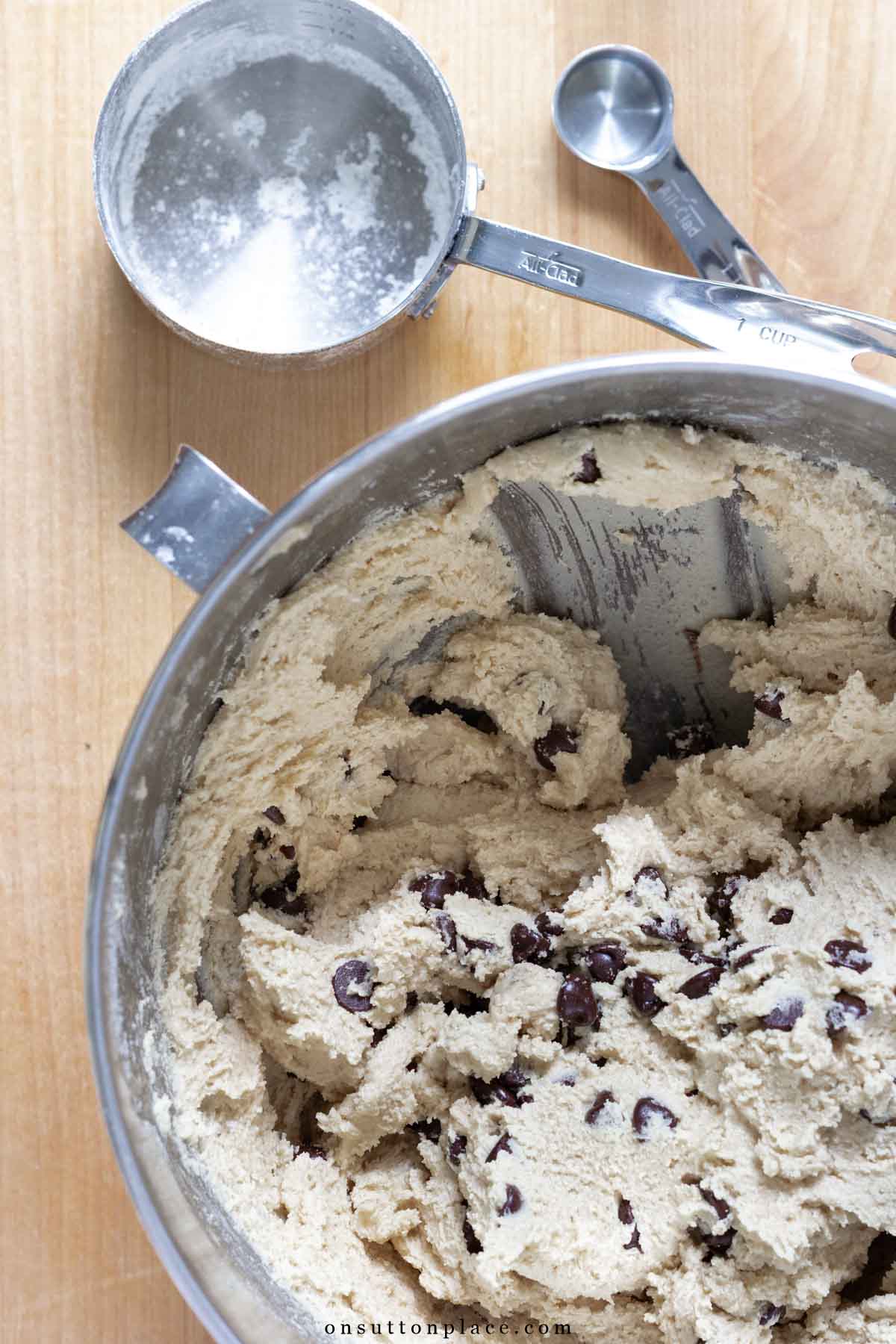 chocolate chip cookie dough in mixing bowl with measuring cup and spoon