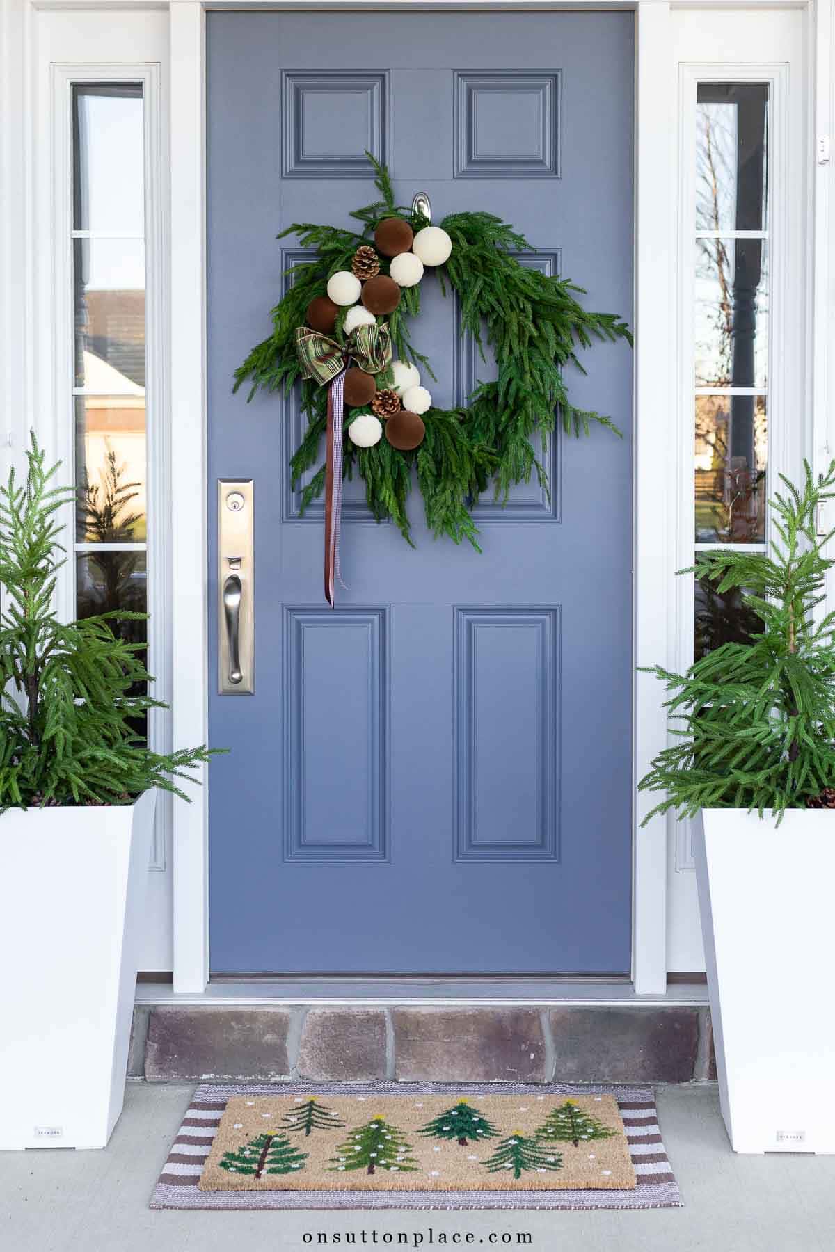 blue front door with Norfolk pine wreath brown ribbon