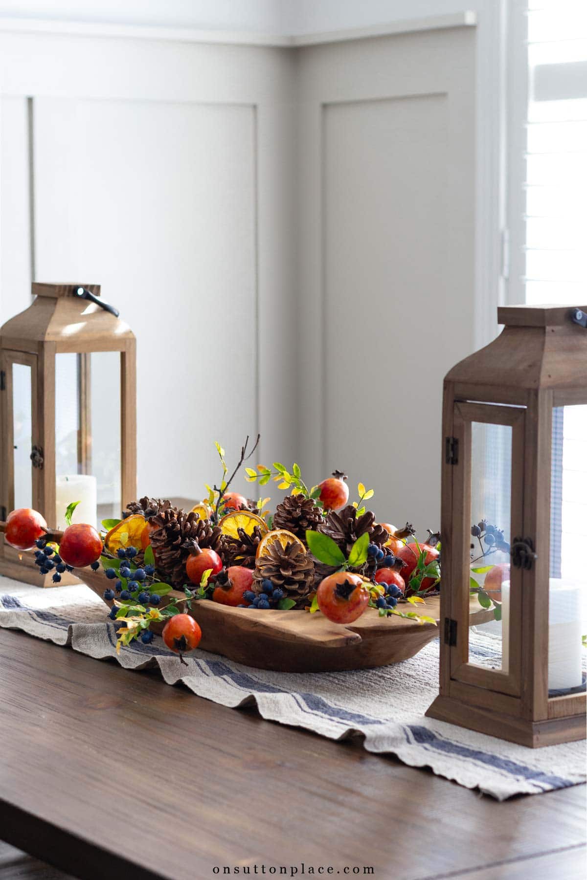 holiday centerpiece in dough bowl with lanterns and table runner