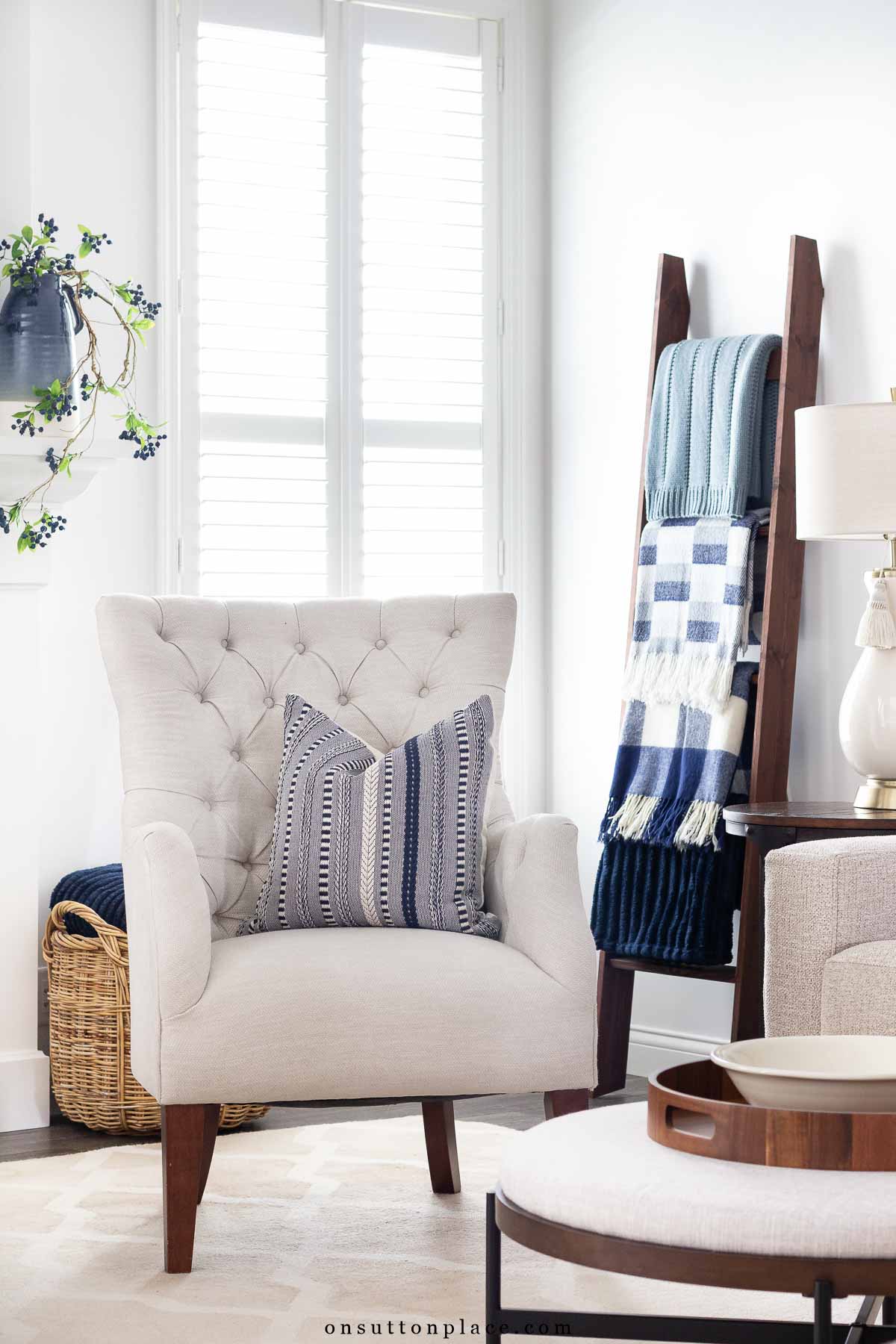 corner of neutral living room blanket ladder tufted chair ottoman coffee table