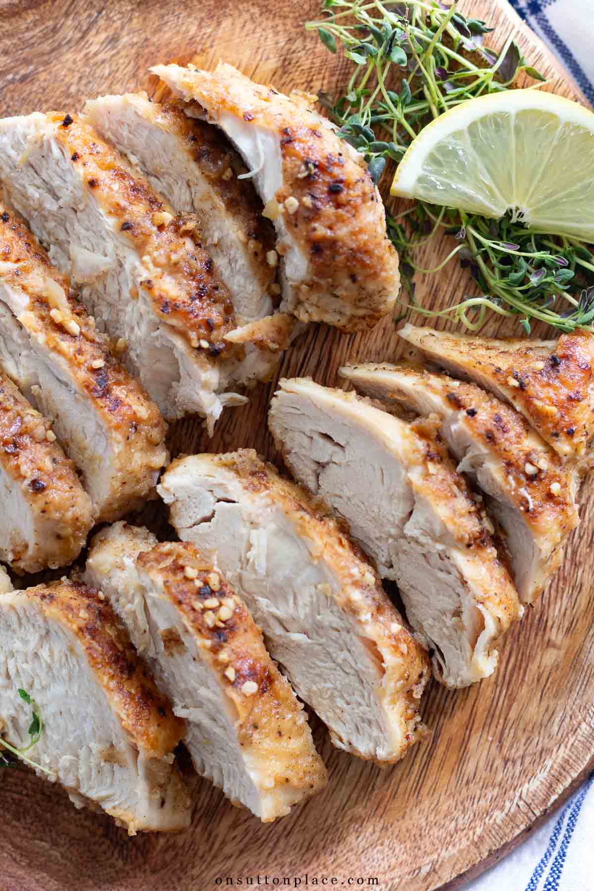lemon chicken recipe sliced on wood board with lemon and thyme
