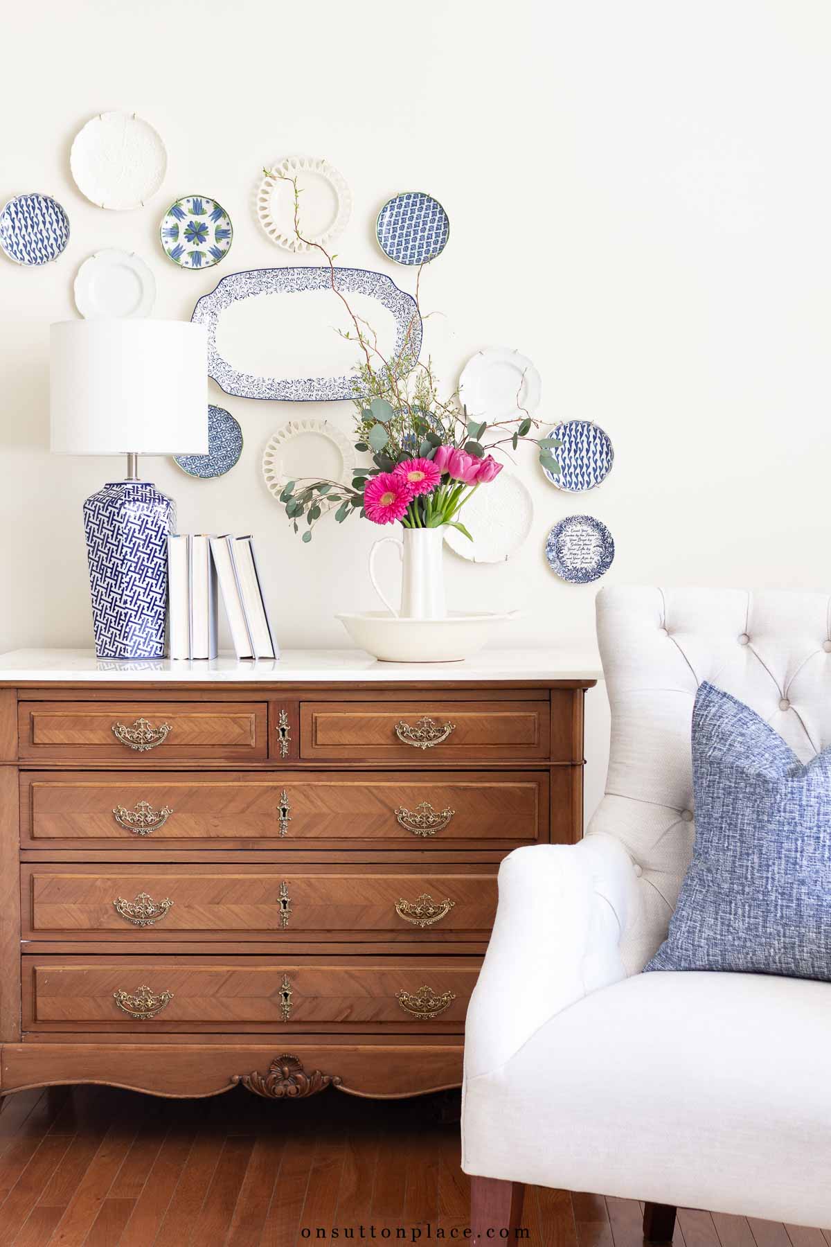 antique dresser in neutral living room with tufted chair