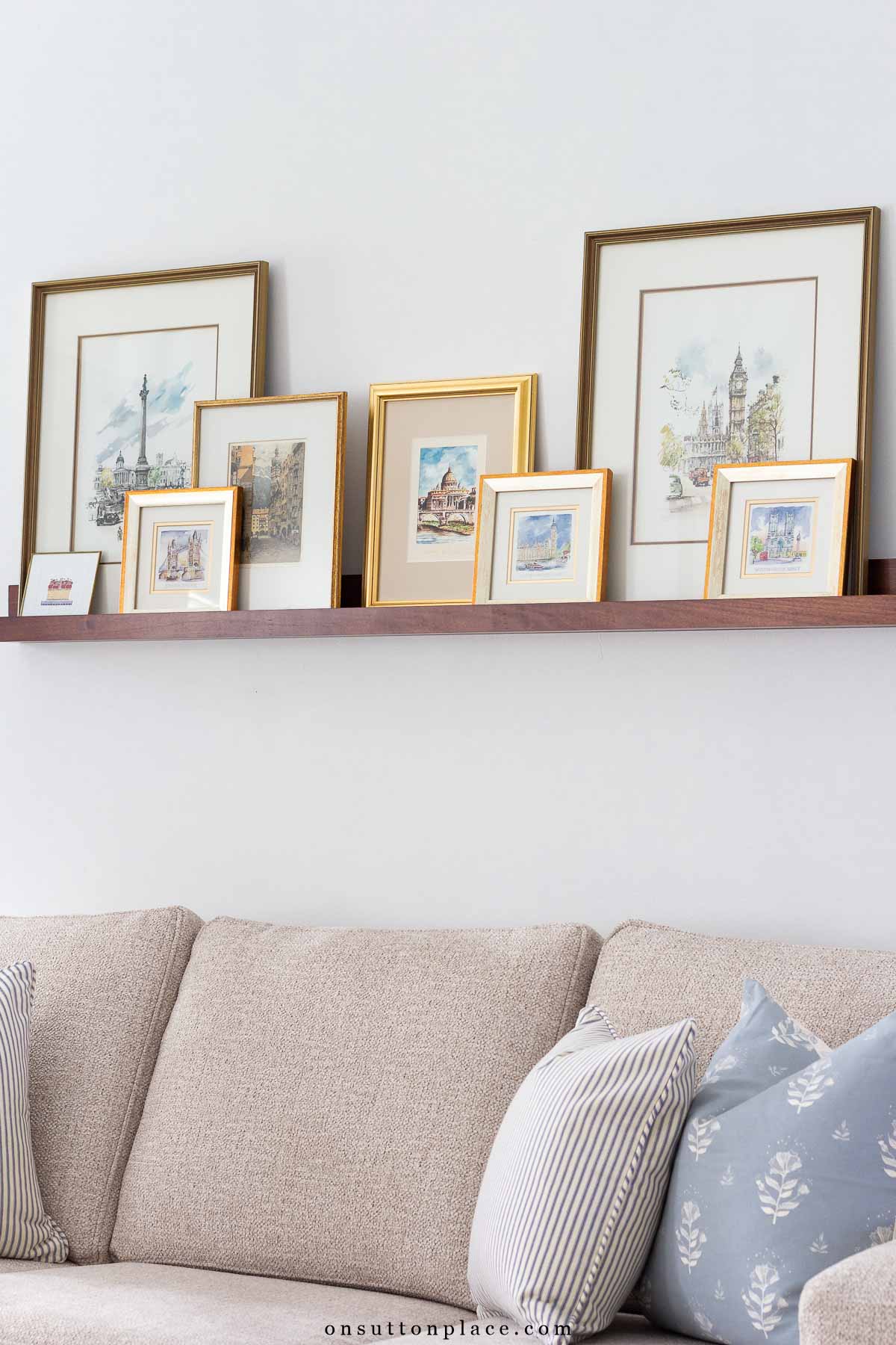 picture ledge over sofa in neutral living room various frames