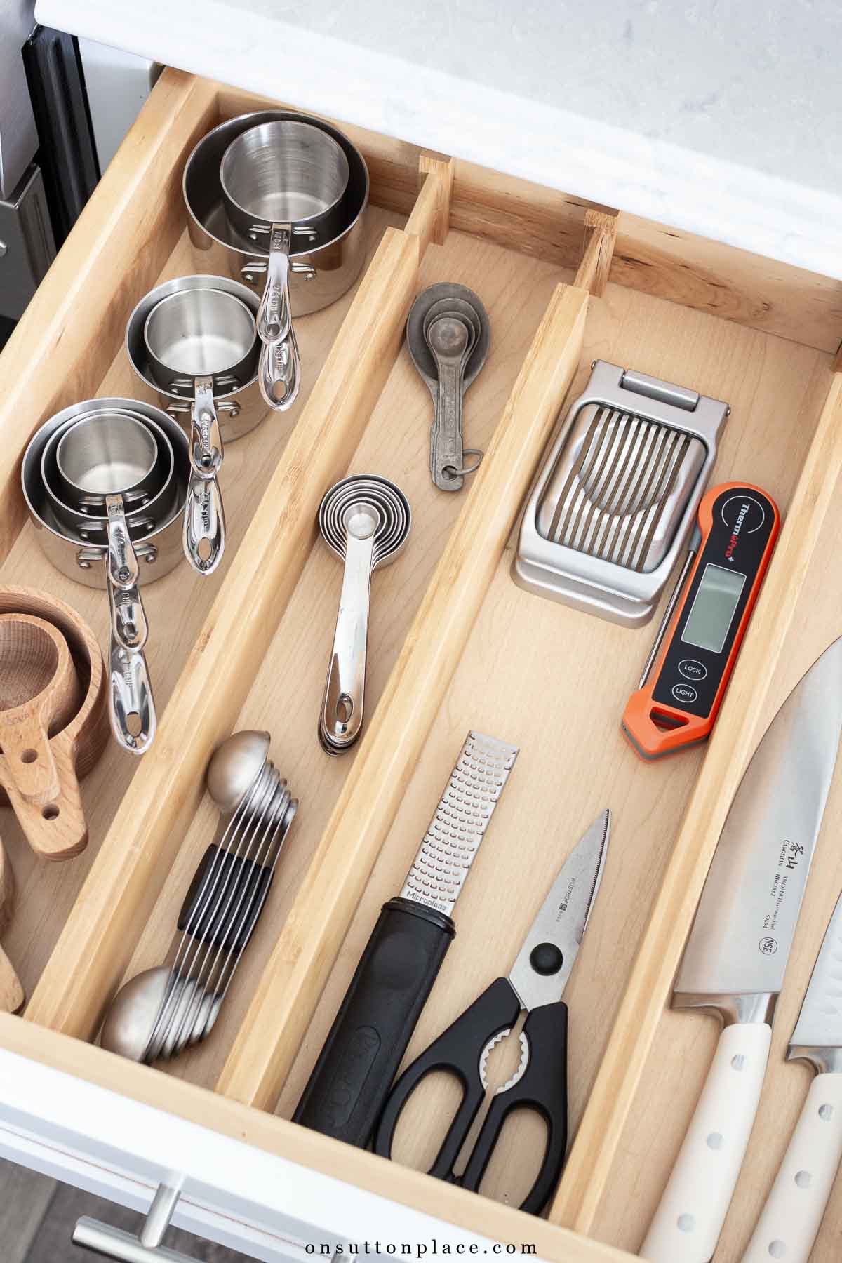 measuring cups and spoons organized in kitchen drawer using drawer dividers