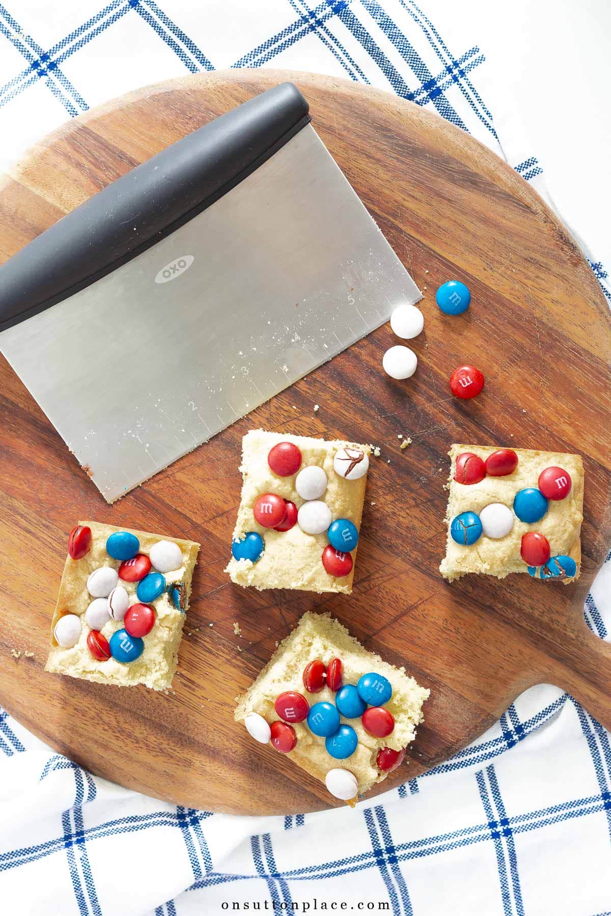 m&m cookie bars with slicer on wood board