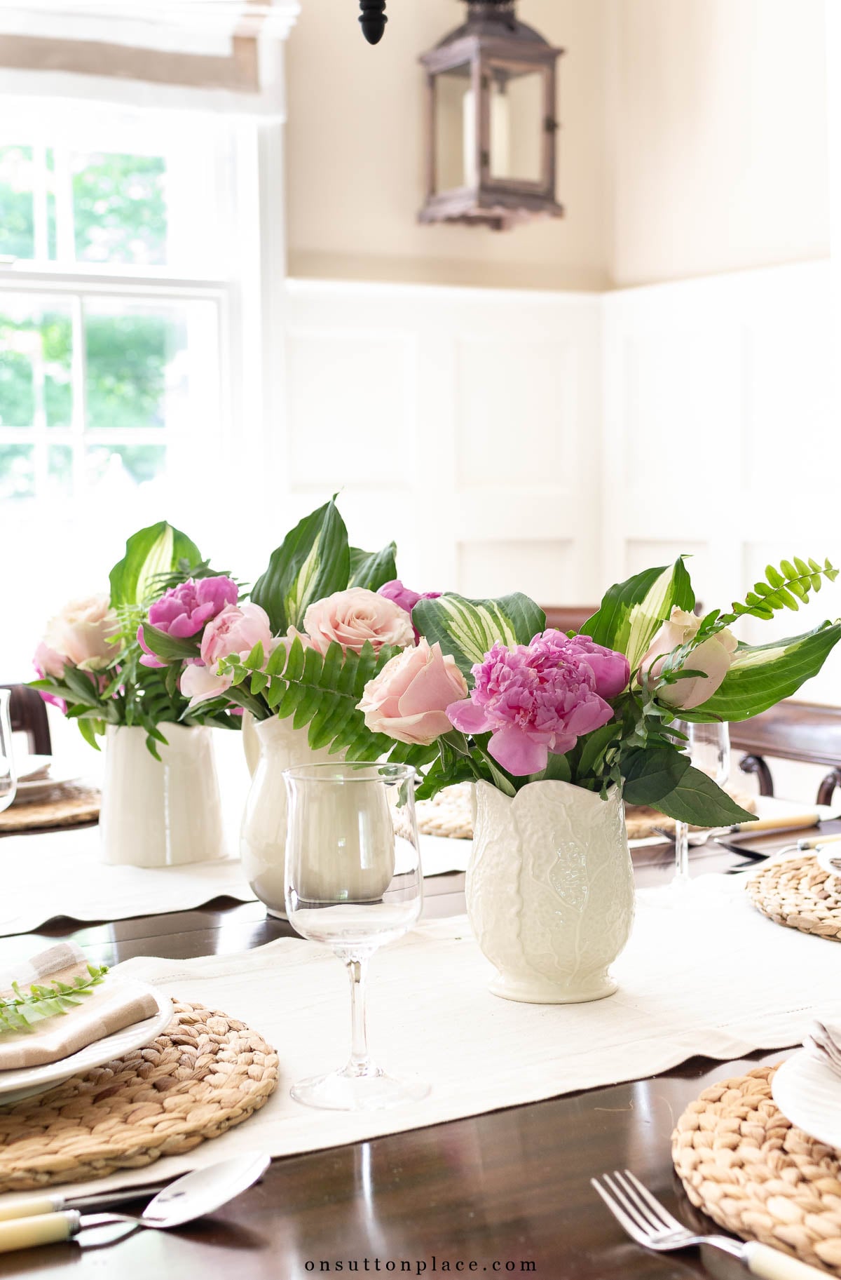 pitchers of pink peonies and roses on traditional dining room table