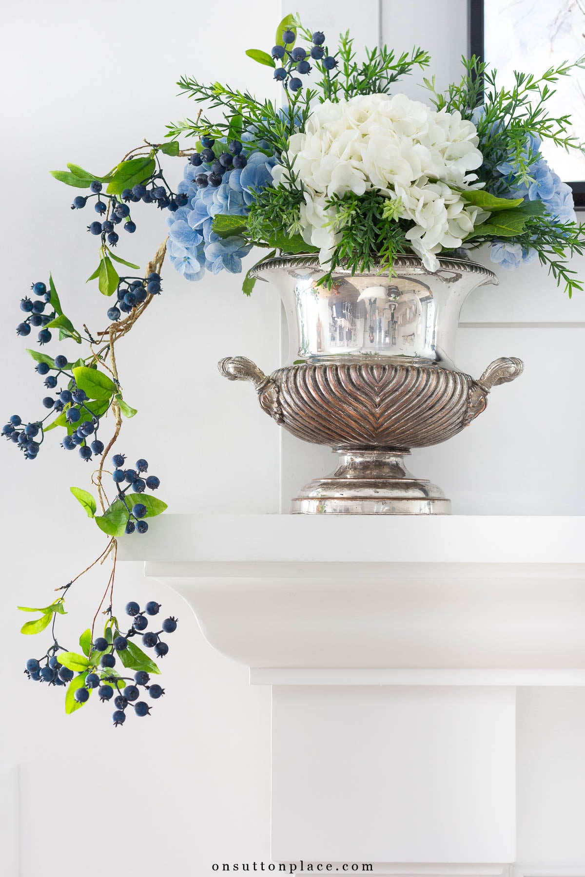 silver urn with faux hydrangeas on mantel
