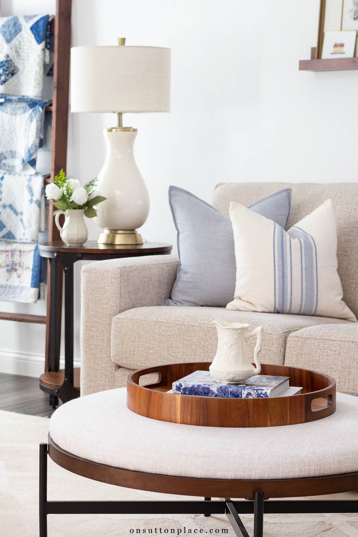 upholstered ottoman used as coffee table in neutral living room